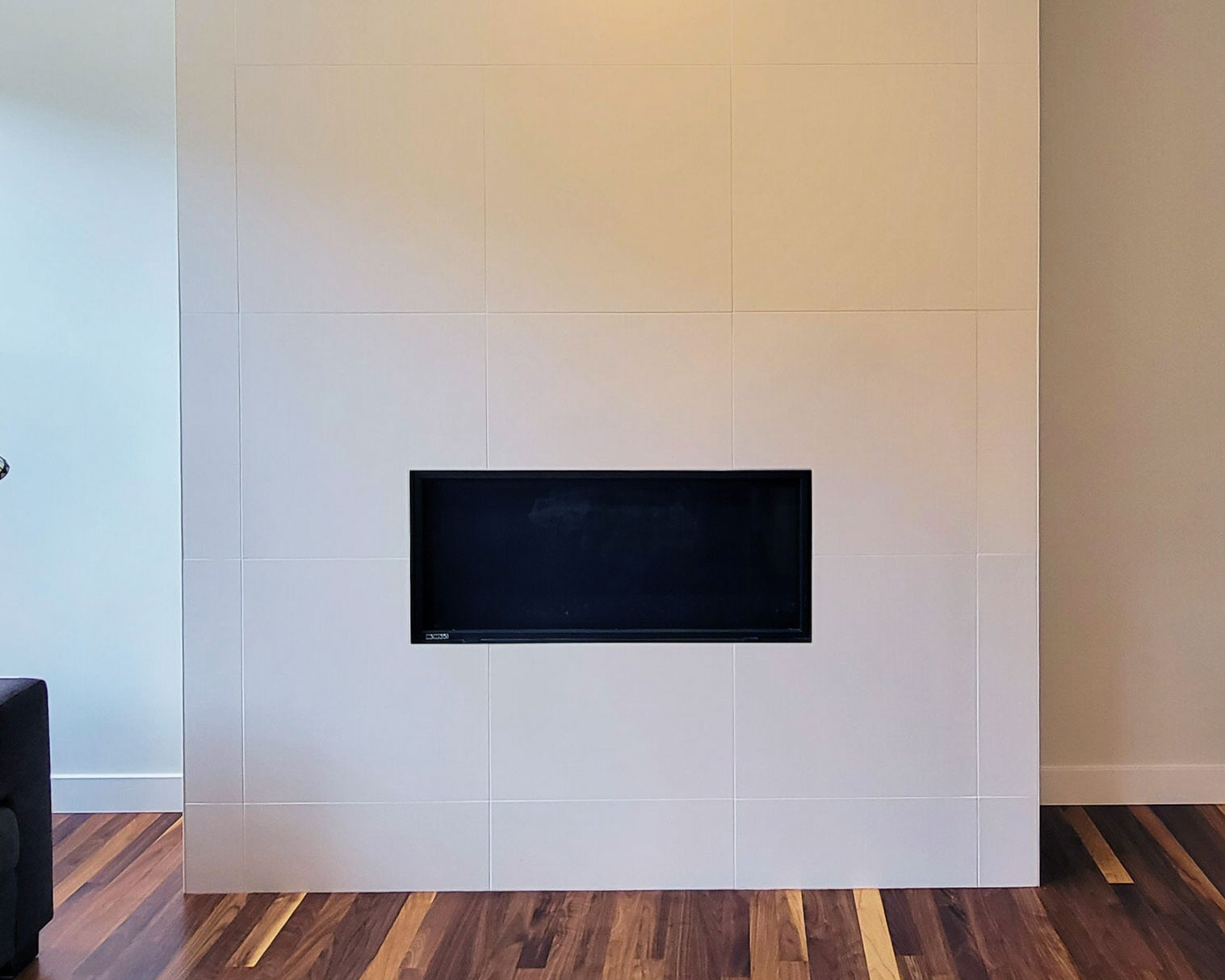 Image of Modern electric fireplace with white tile surround and wooden floor, KHD Homes interior design construction.