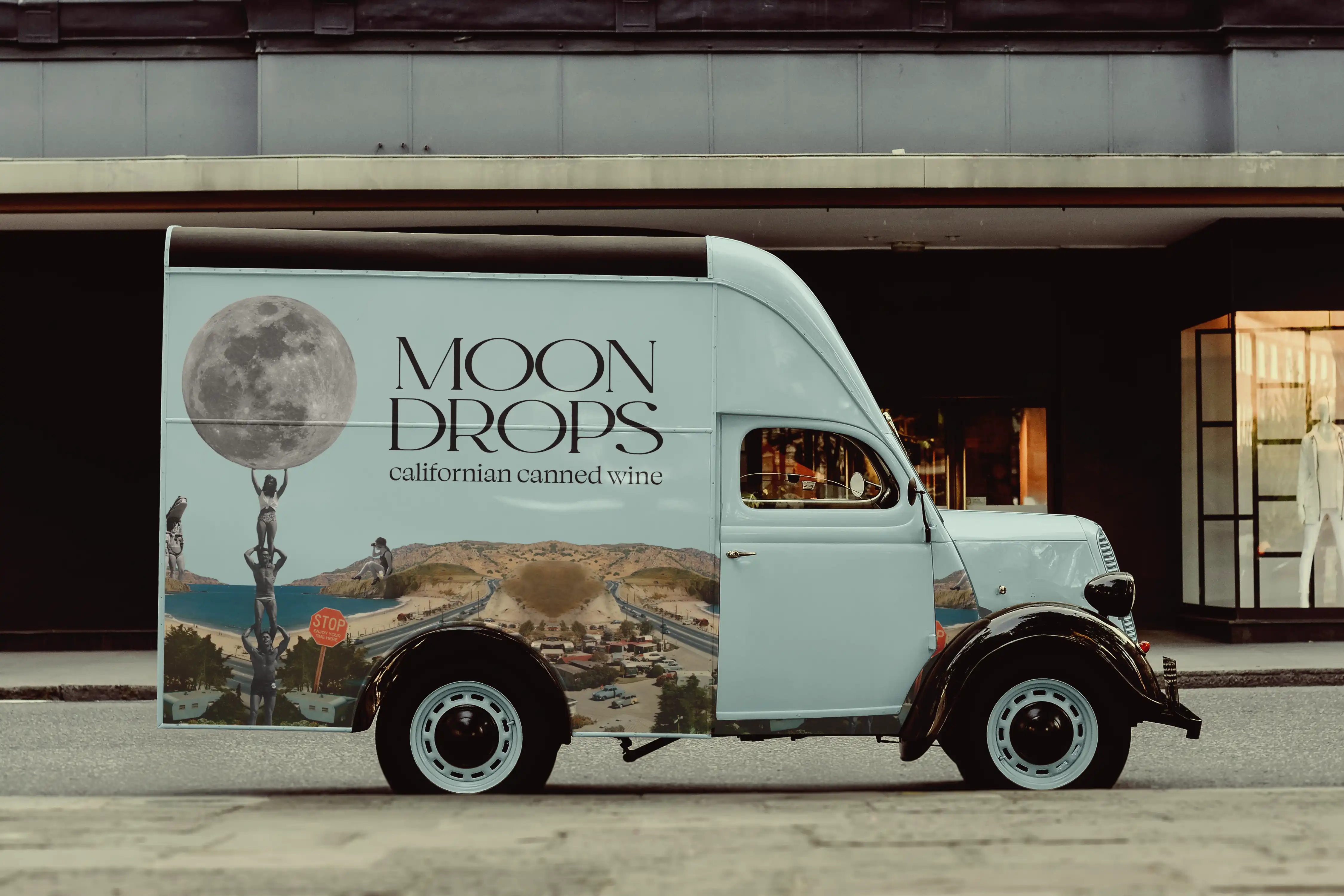 A vintage style truck in a duck egg blue with a collage and the words moon drops on the side.