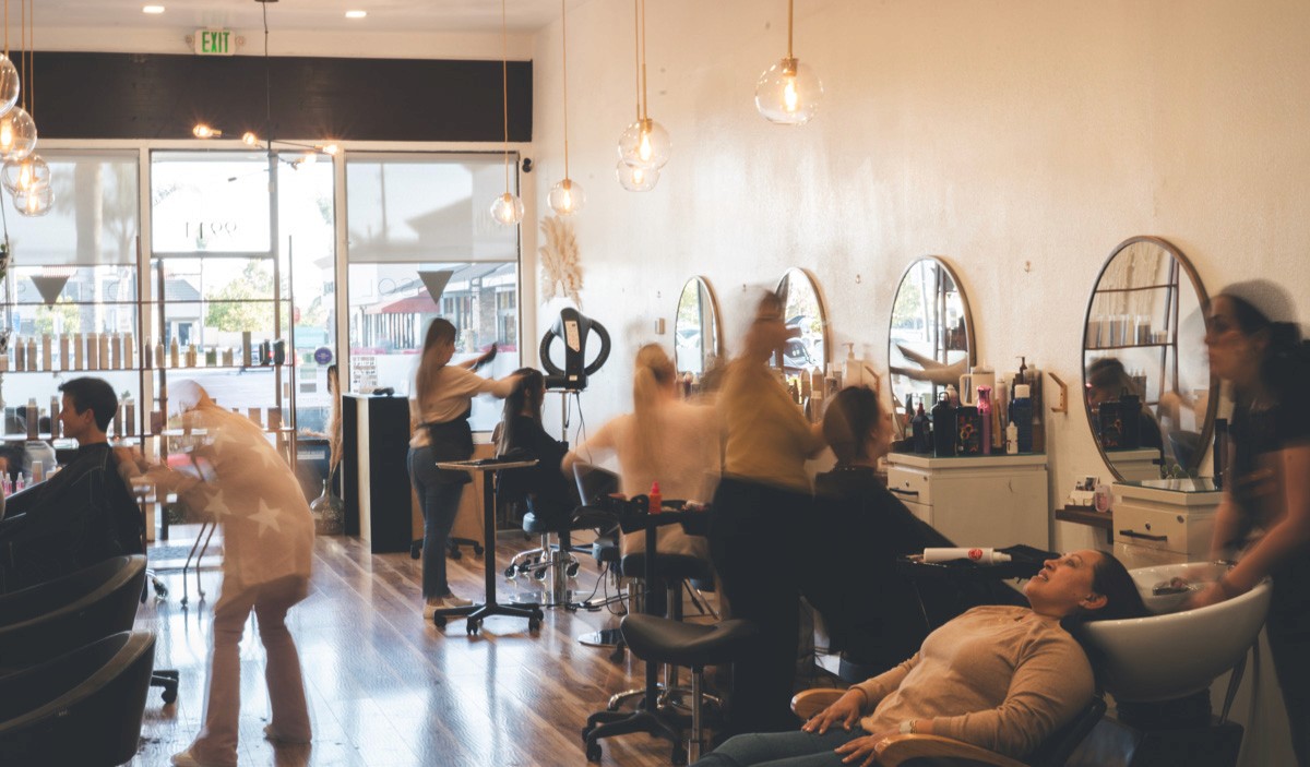 Del Sol Hair Studio interior bustling with stylists actively working with clients, capturing the welcoming energy and full-service atmosphere of the salon.