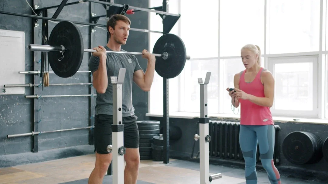 Man lifting weights with woman watching