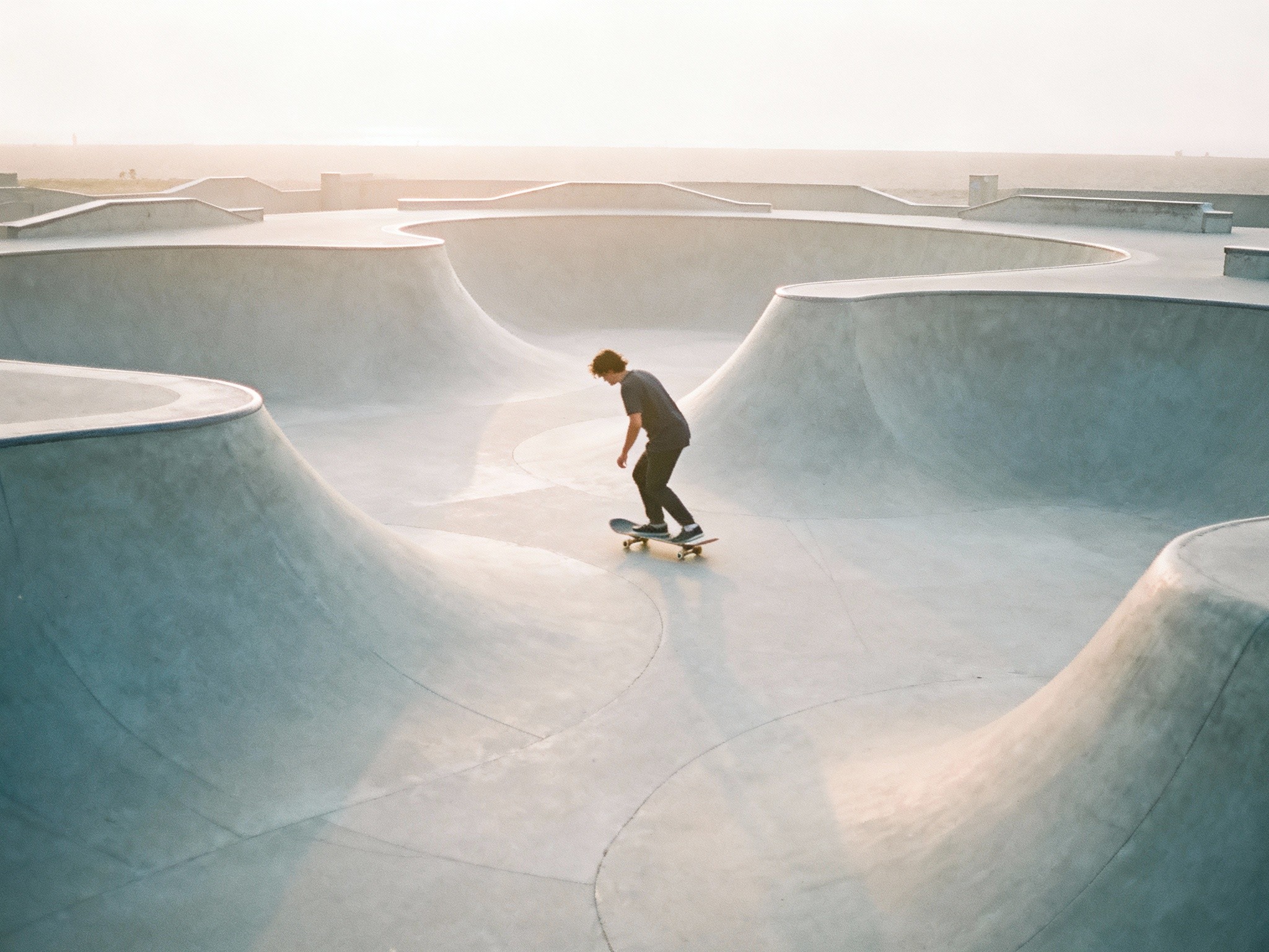 An early morning serene skate park scene featuring a solitary skateboarder practicing tricks on