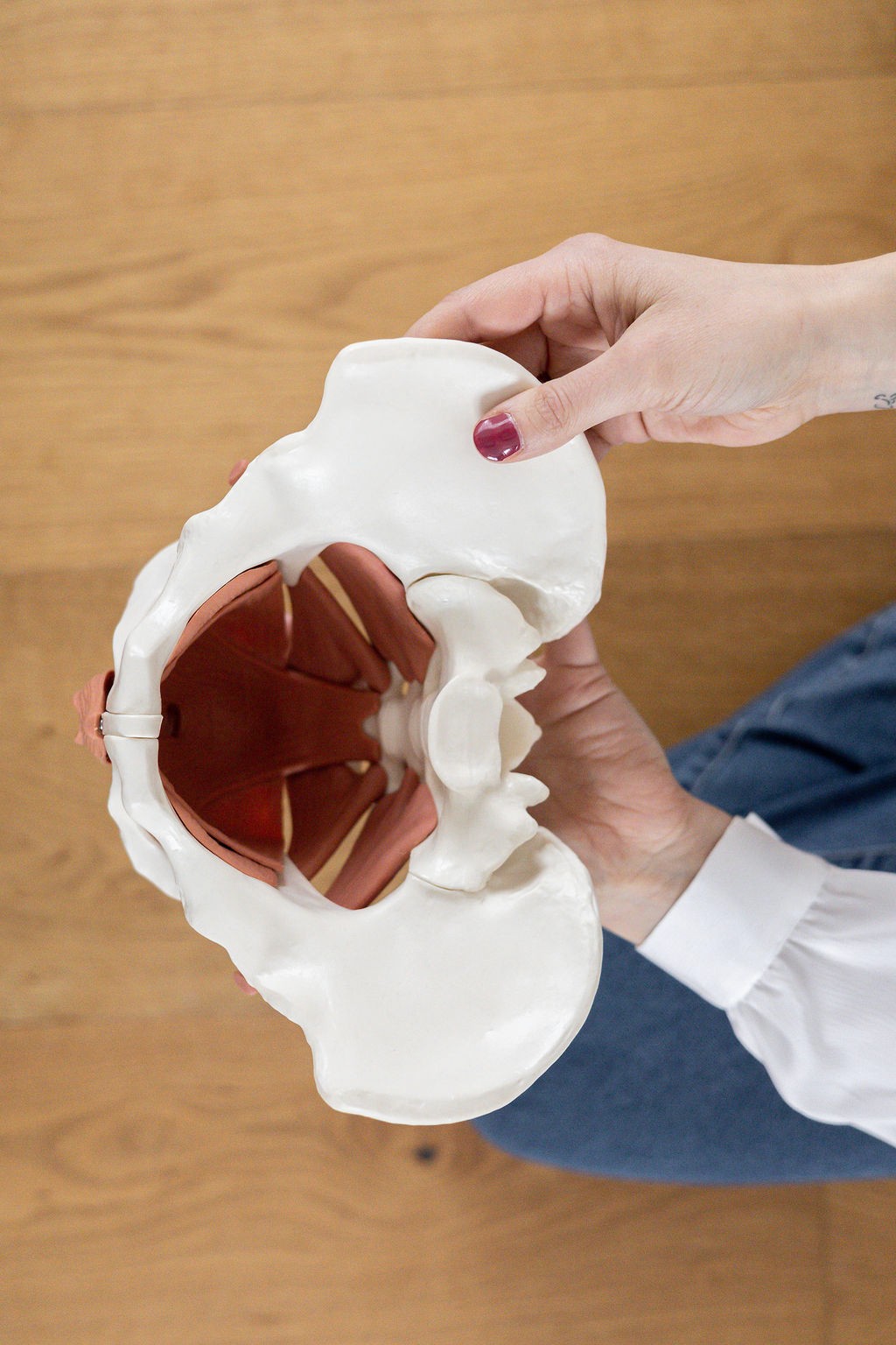 Smiling female therapist with short gray hair, wearing a brown top and a purple shawl, surrounded by a cozy background.