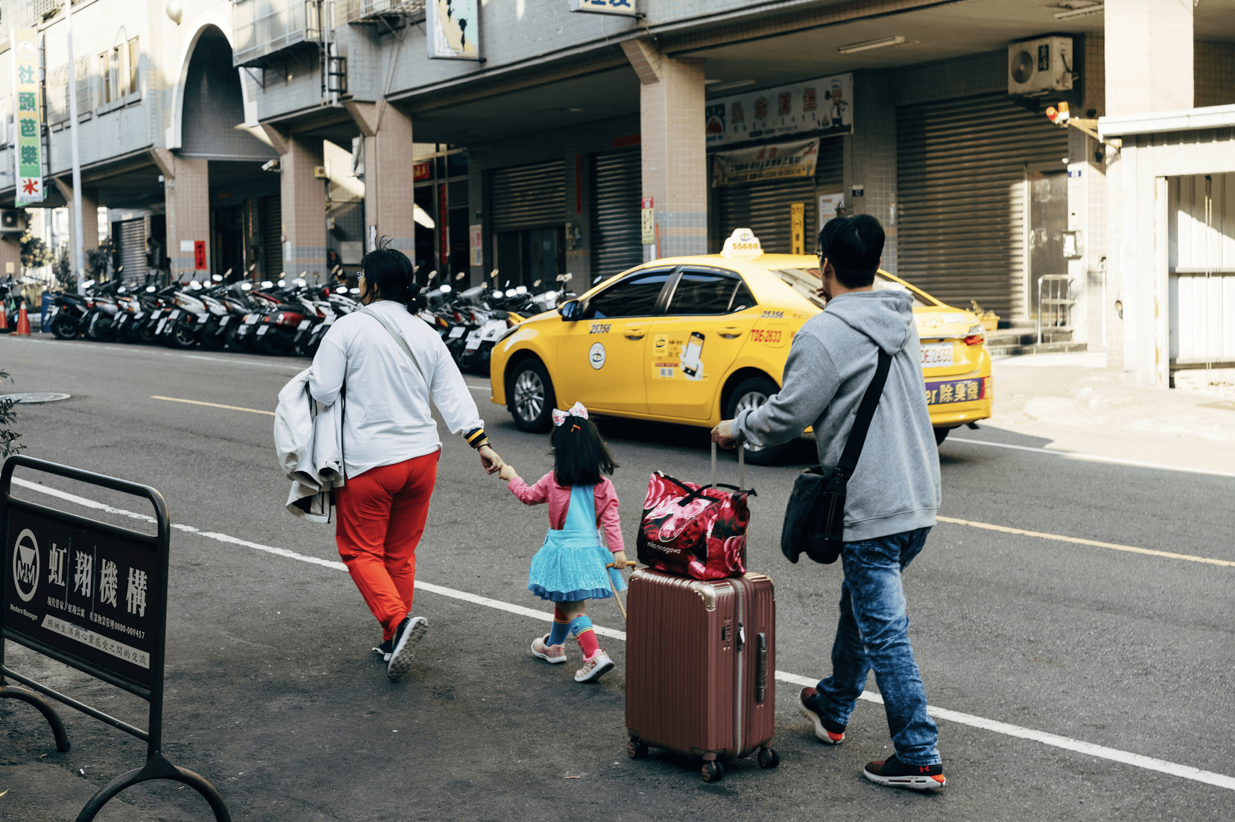 tourist family walks down a street with luggage