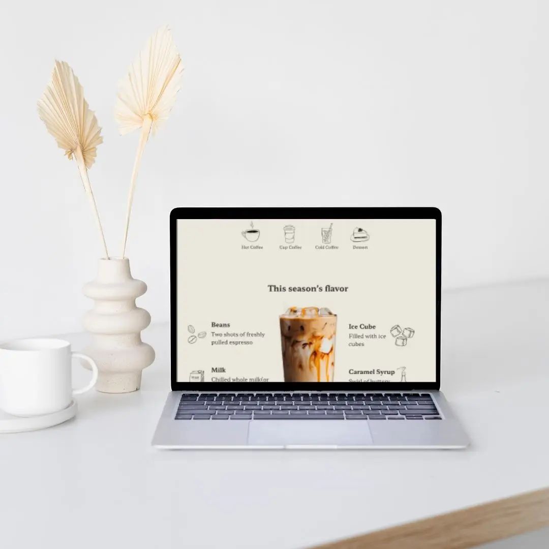 Computer der viser kaffe websitet, omgivet af vaser og kaffe kop