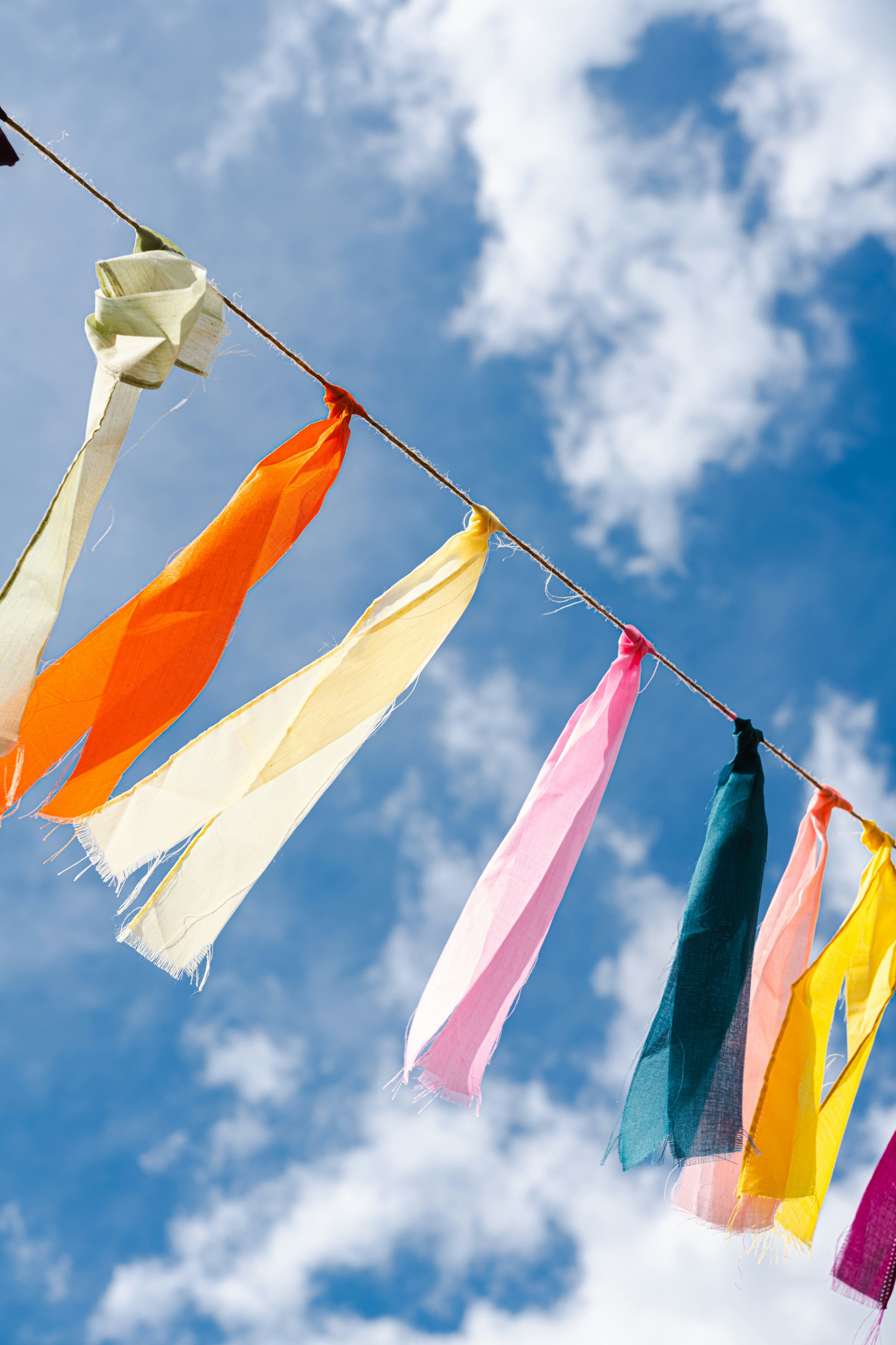 Colourful silk and fabric strips hanging from a line against a blue sky