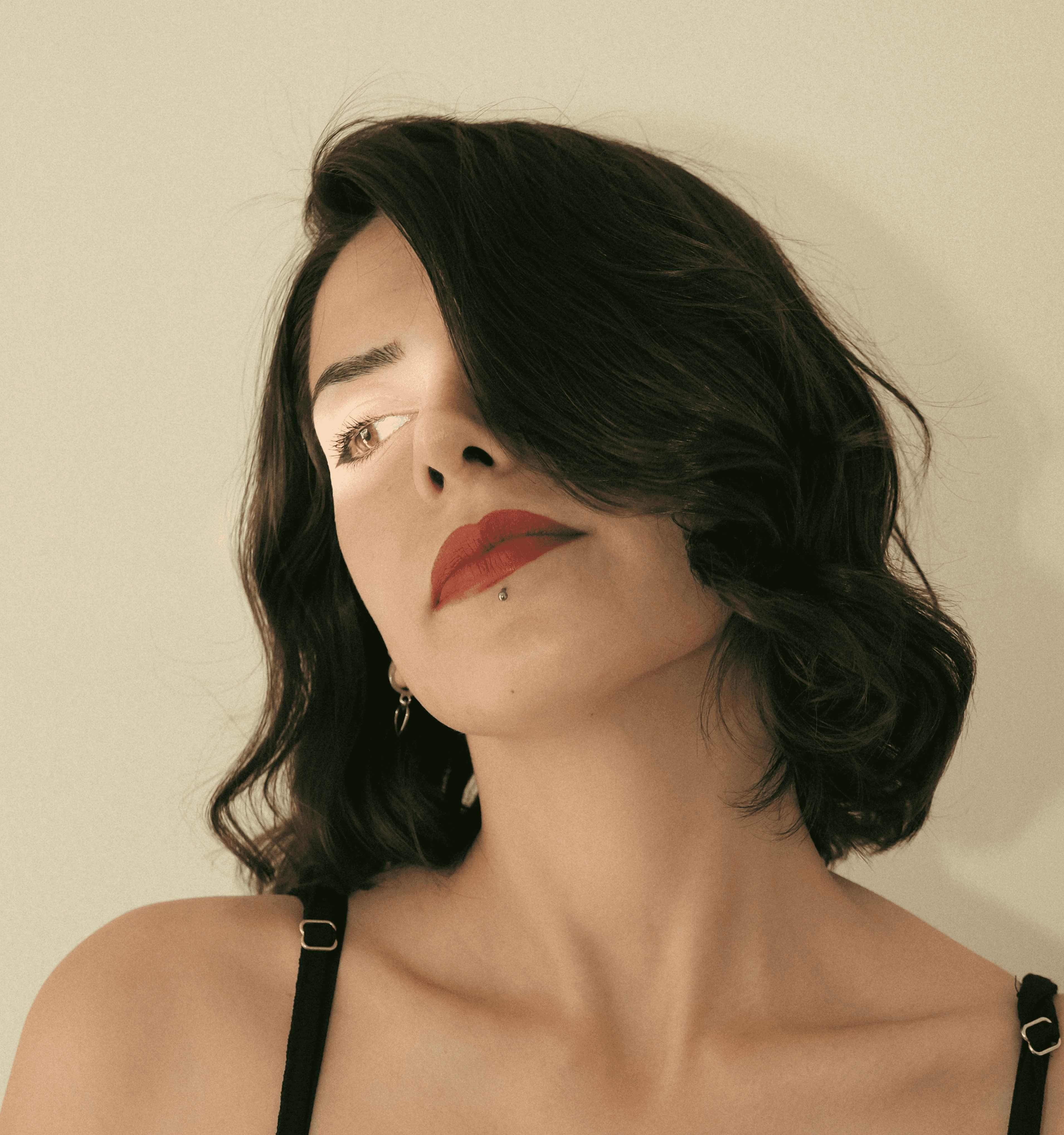 Minimalist profile shot of a man with long braids and a white shirt, set against a soft, light background.