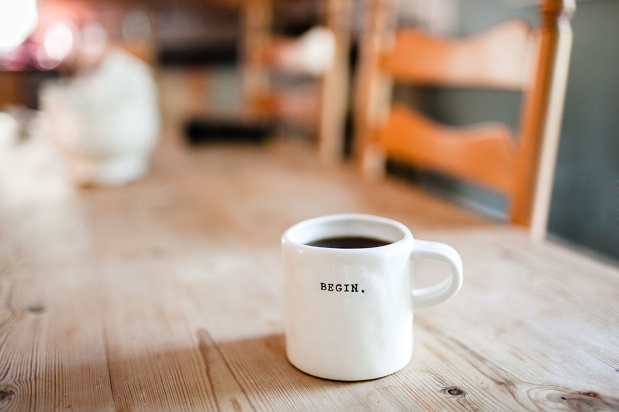 White cup of coffee with the words begin to symbolize learning how to hire remotely