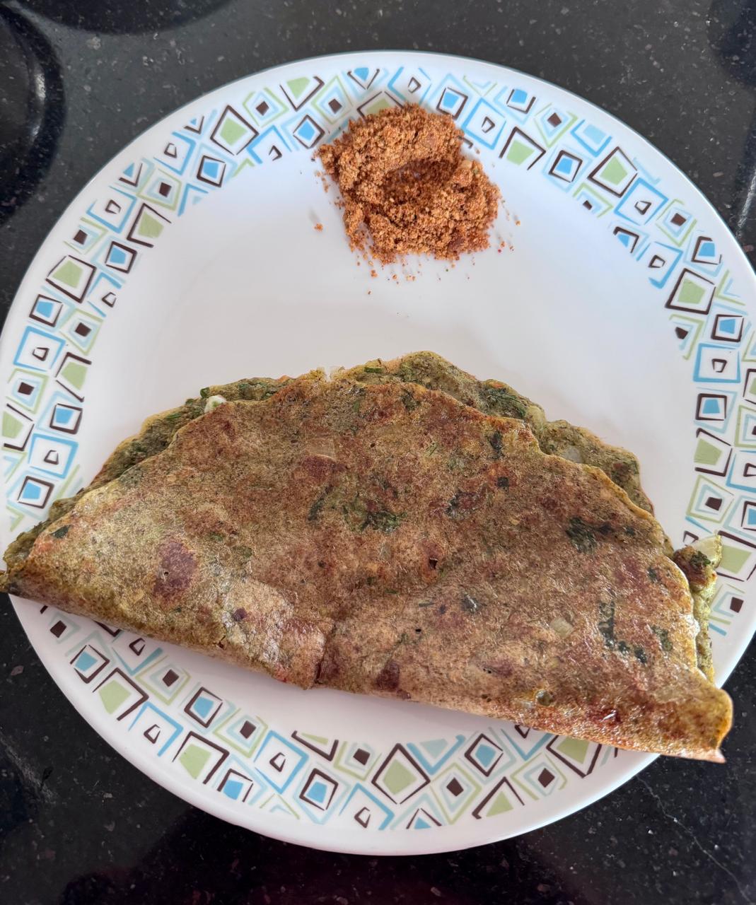 Pesarattu served on a plate with idli-dosa podi