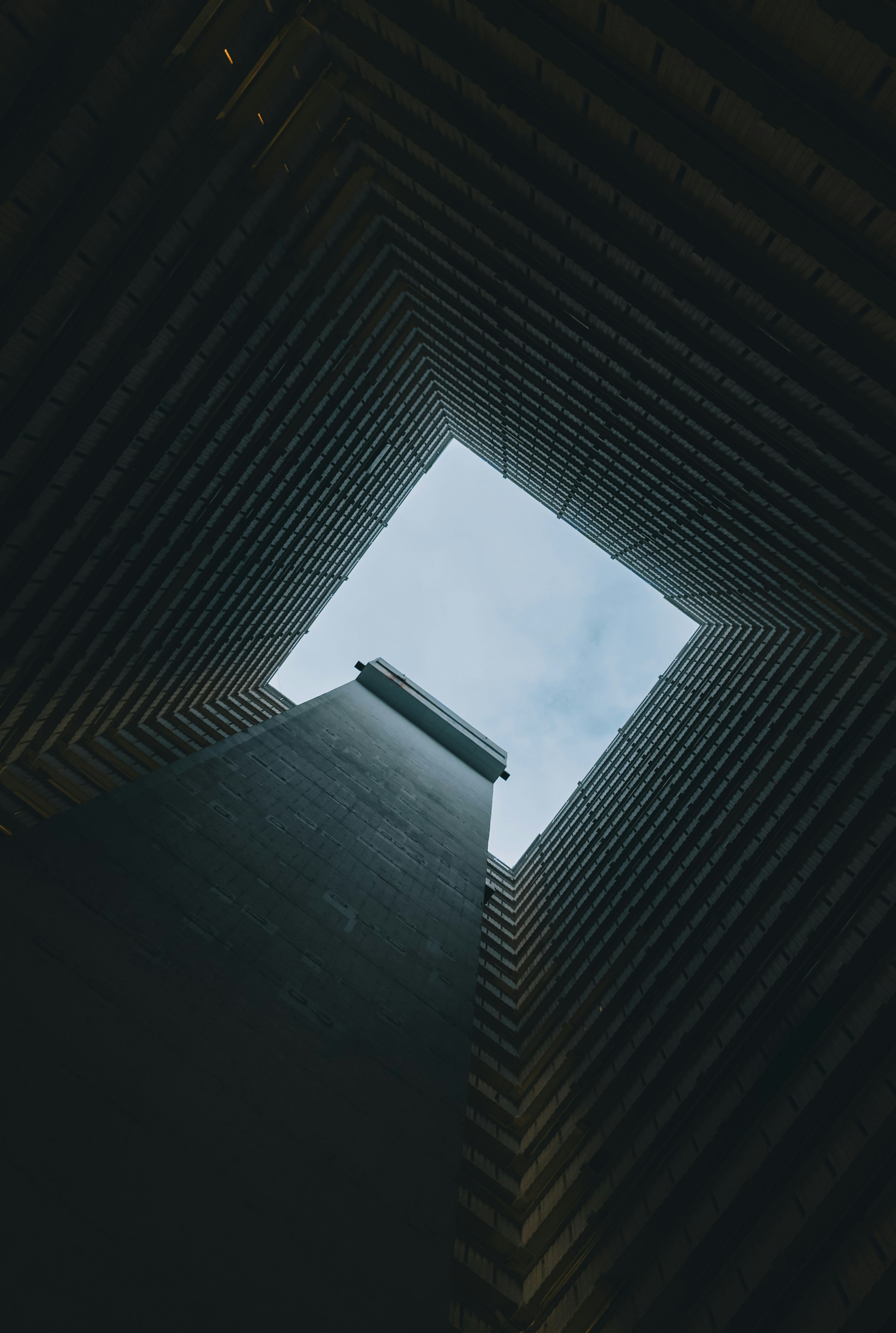 Looking up through a concrete building shaft to sky