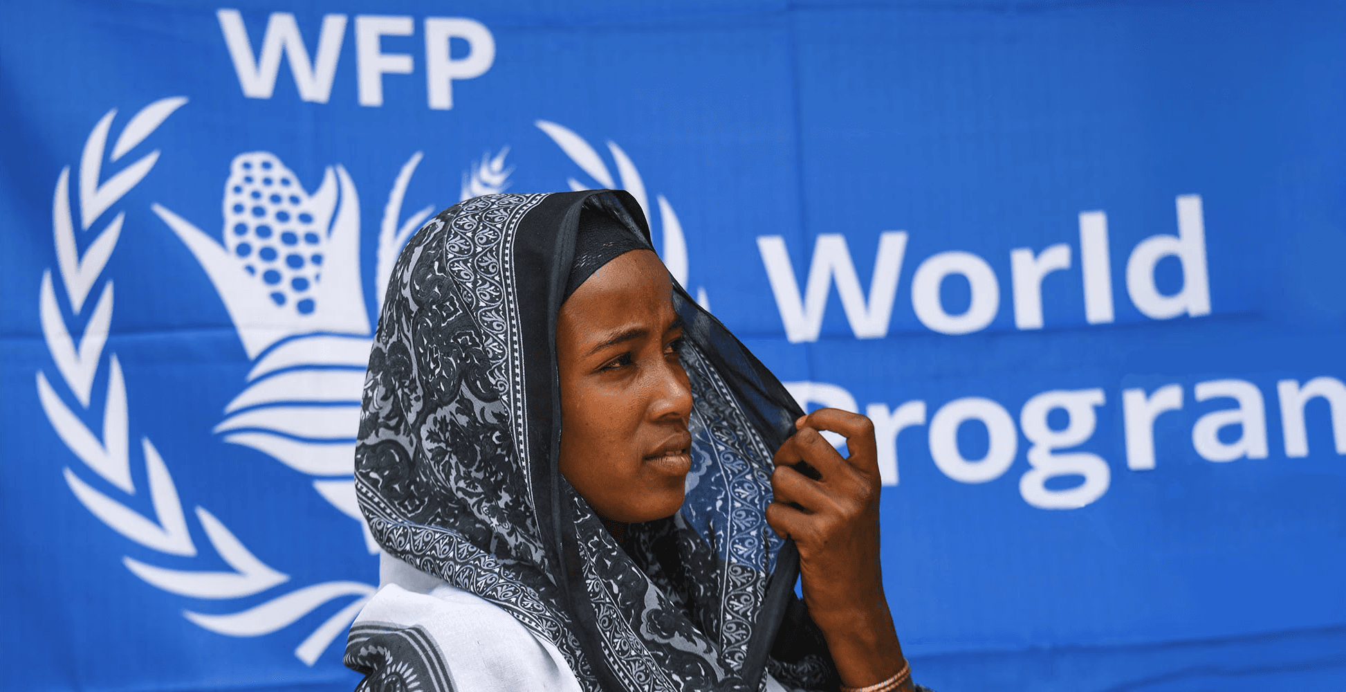 WFP - Donna con velo davanti a un banner del World Food Programme.