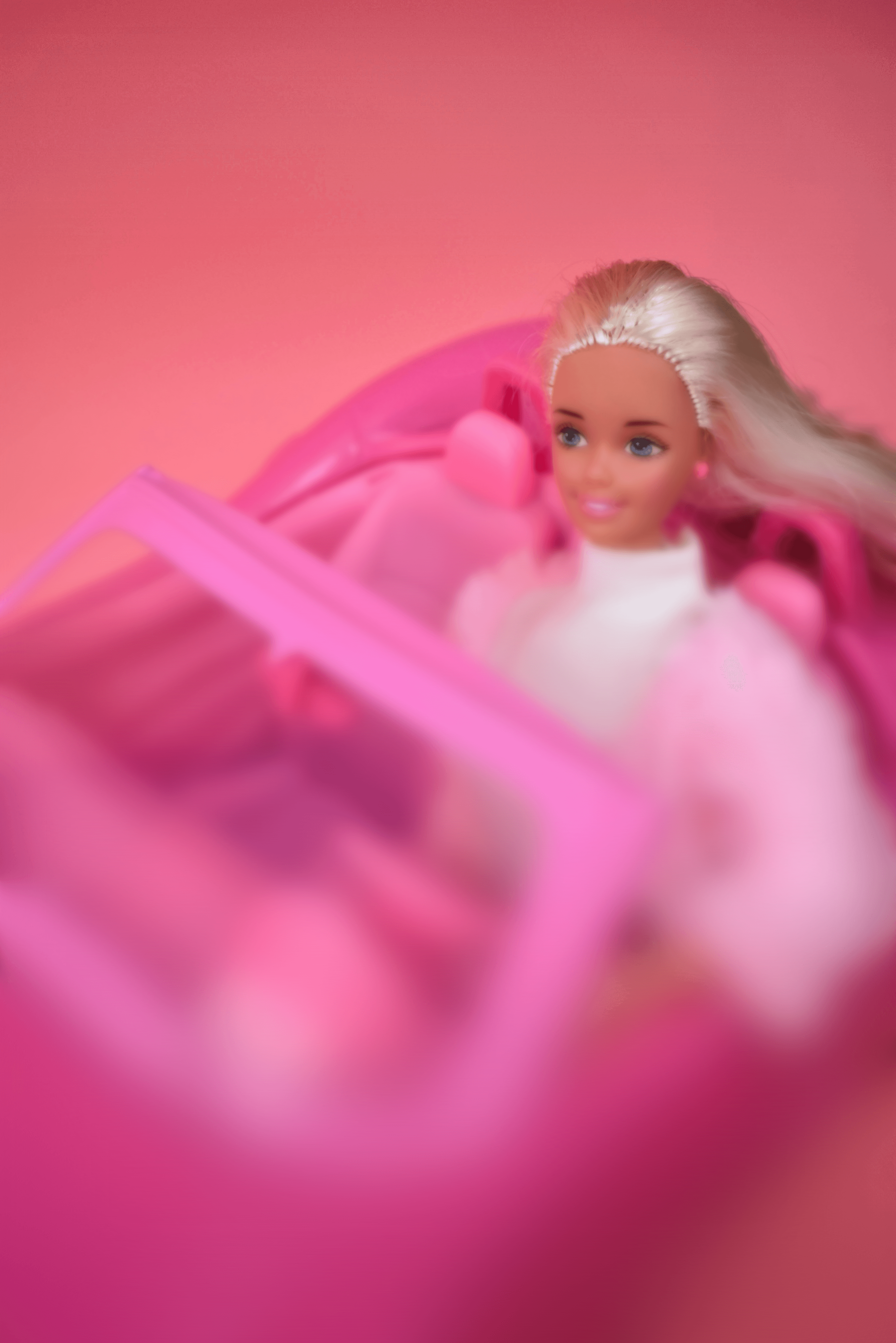 A barbie doll sitting in a pink car