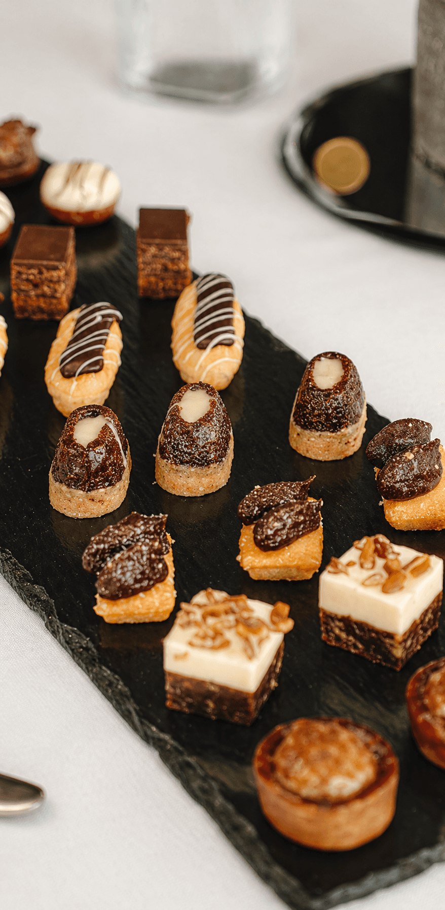A dessert table piled with coconut balls,  chocolate squares,  almond tarts