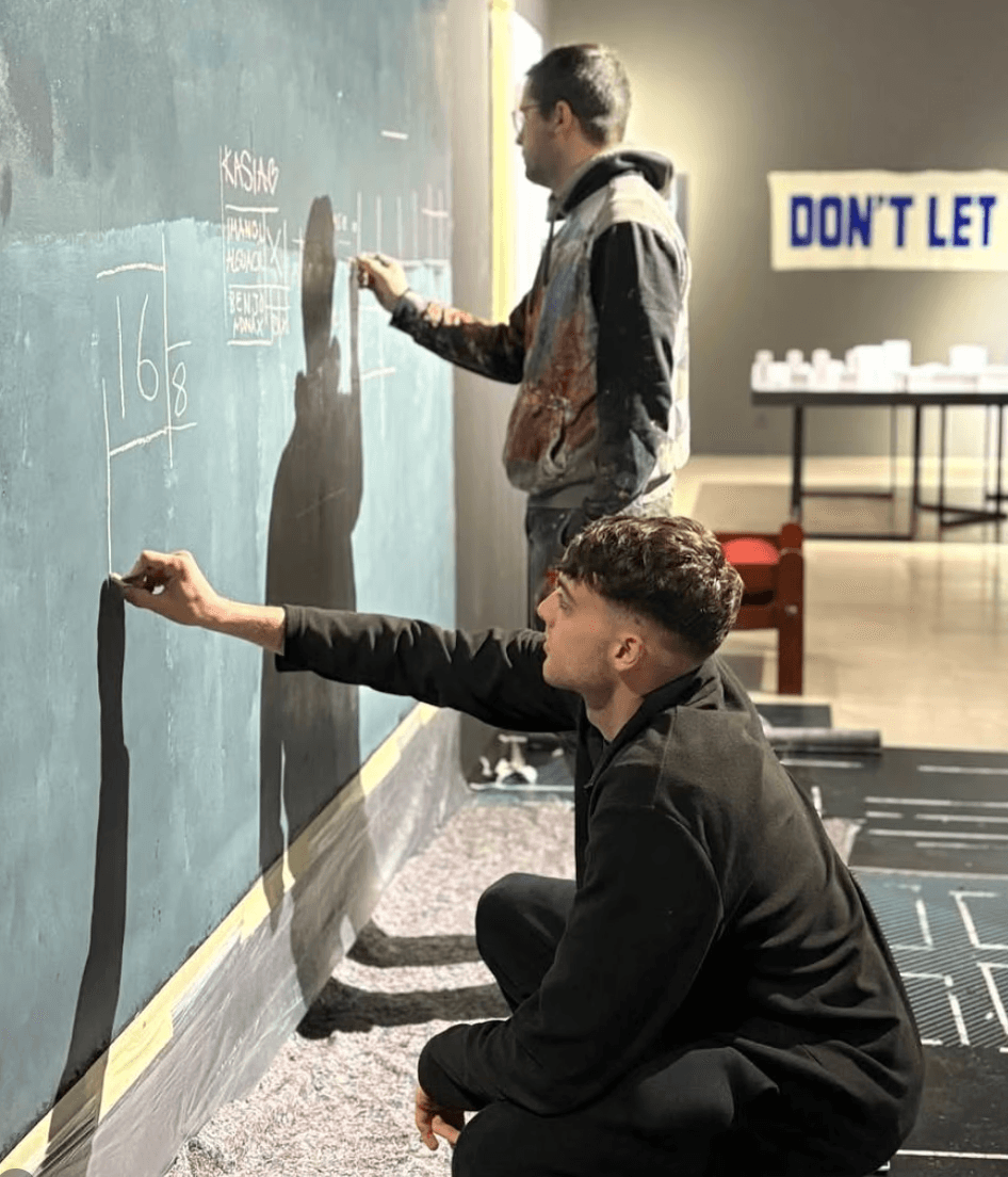 Film clapperboard in focus with glowing orange background, misty street, and silhouettes of people and lights; conveys mystery and anticipation.