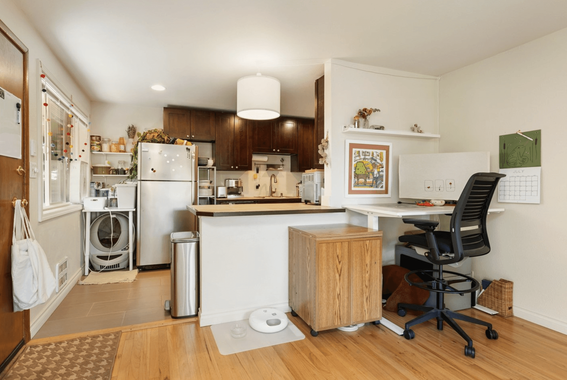 Futuristic white house with organic, curved architecture set on a green hillside surrounded by trees and dramatic cloudy sky.