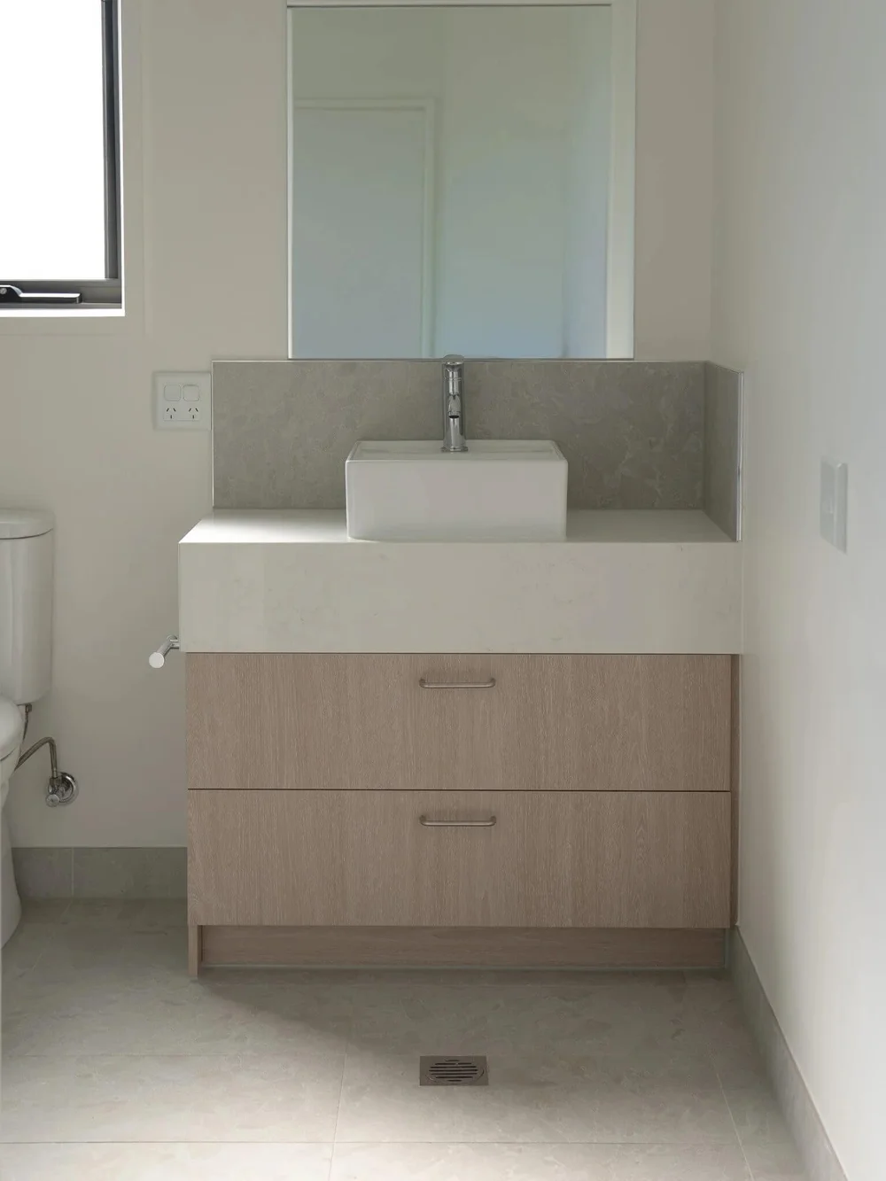 Modern bathroom vanity with rectangular sink and large mirror.