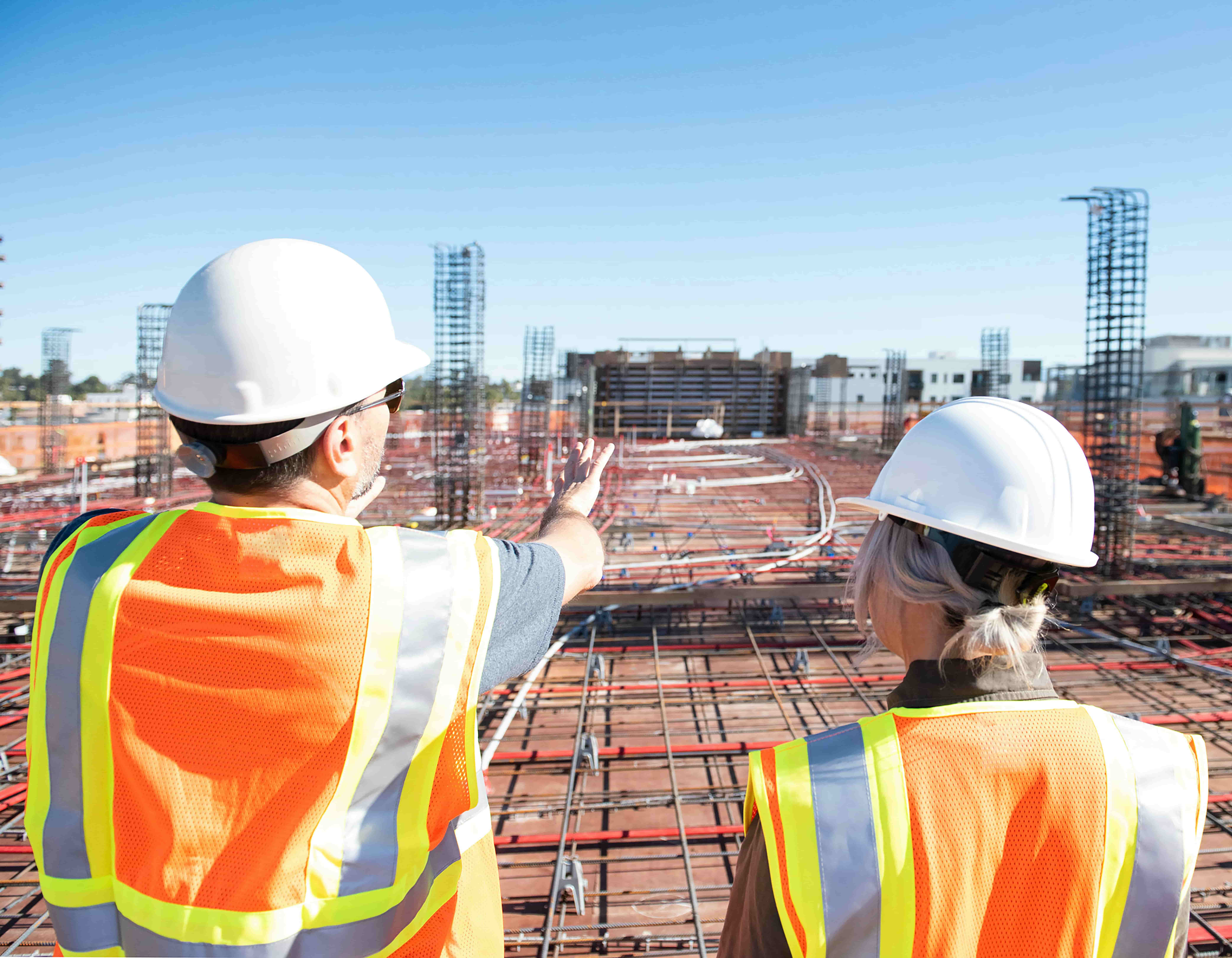 Construction workers reviewing site progress with rebar foundation, representing on-site support for building projects