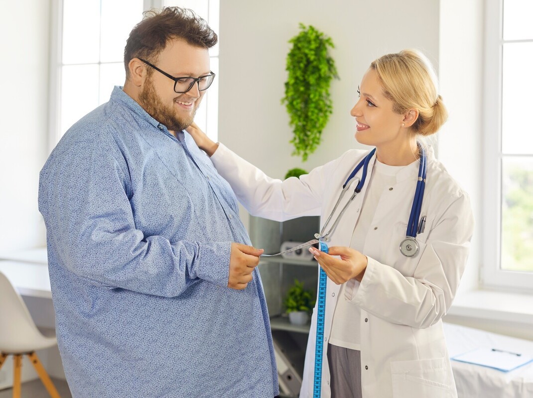 overweight man in a doctor’s office talking to his physician to discuss if walking a mile a day to lose weight is right for him