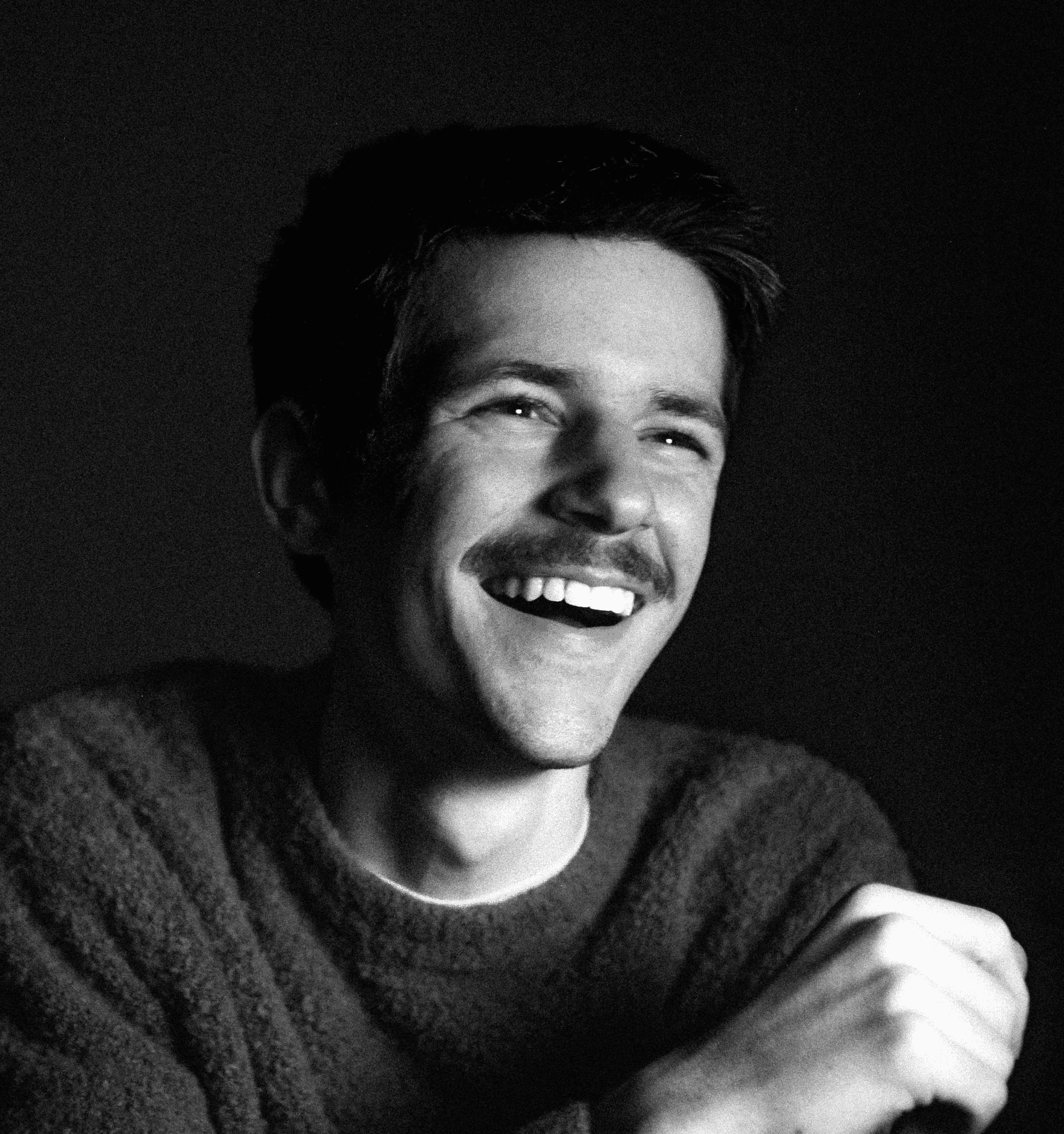Portrait of a laughing person with curly hair wearing a white shirt