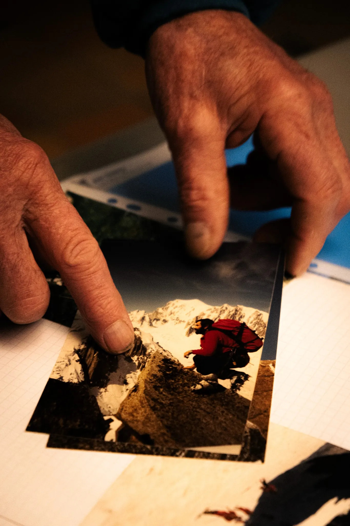 Mains feuilletant des photos d’alpinisme vintage, héritage Millet et passion de la montagne.
