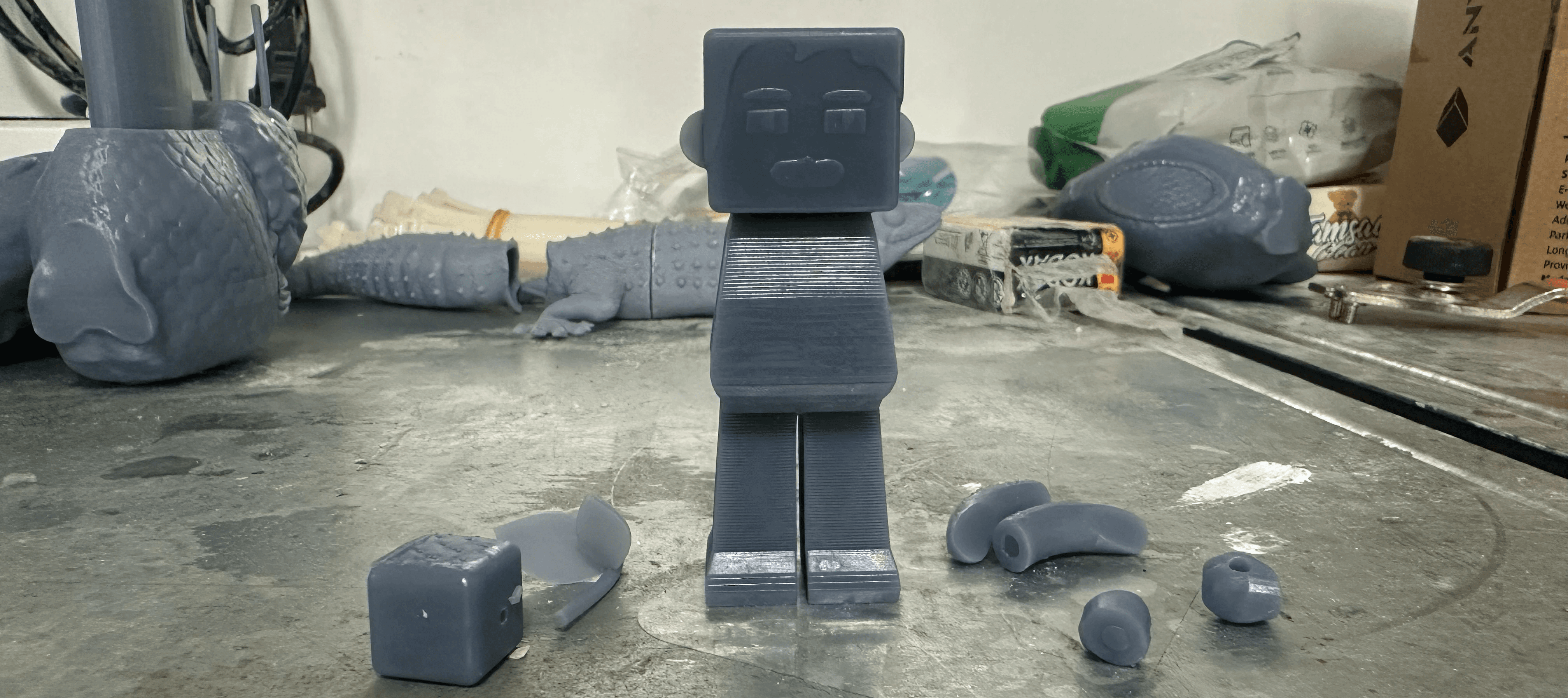 NEMO CREW figure parts fresh off the 3D printer on the studio workbench, mid-process art toy fabrication — 3D 프린팅 출력 직후 작업대 위의 네모크루 피규어 파츠, 아트토이 제작 공정