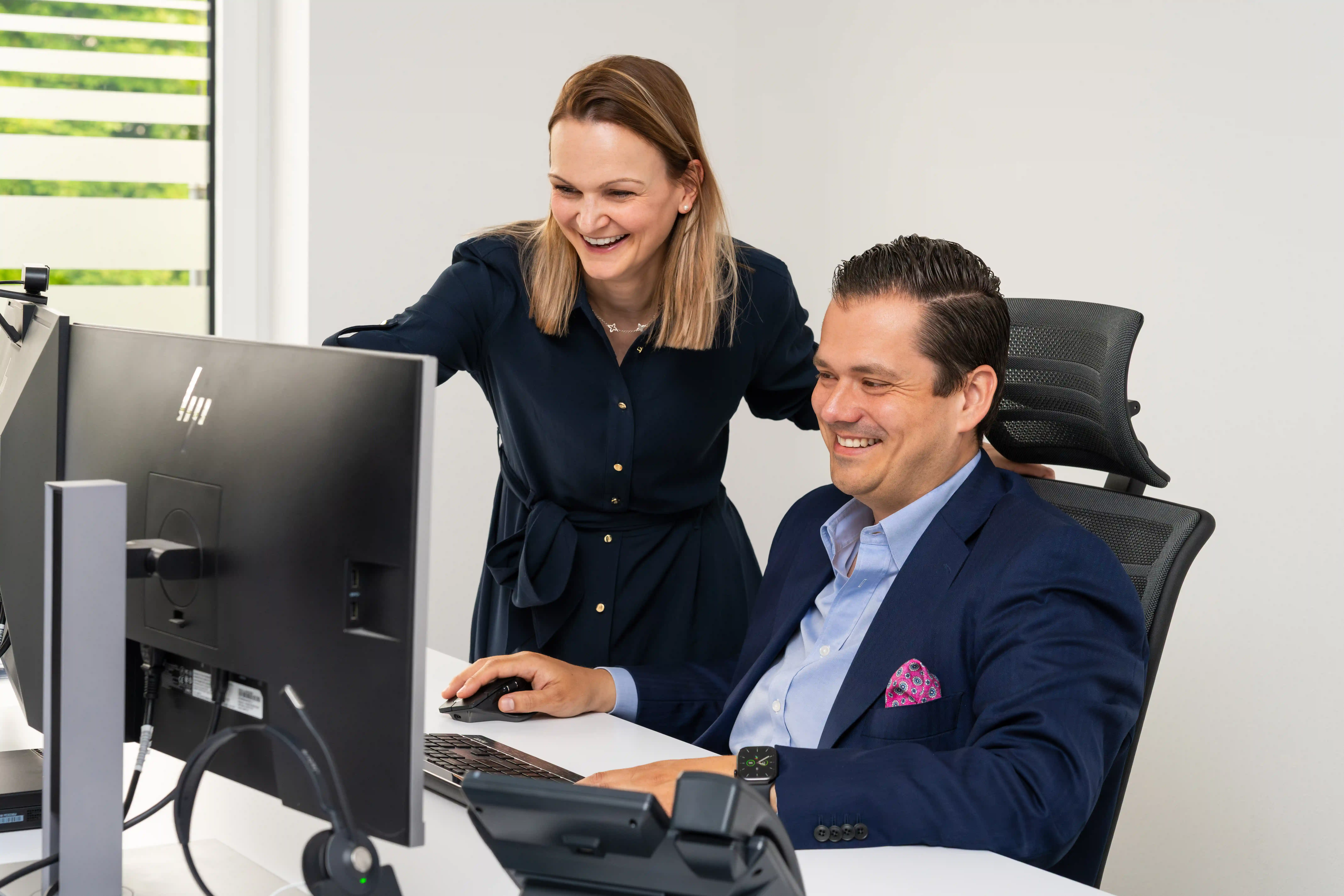 Zwei Mitarbeitende einer Steuerkanzlei arbeiten gemeinsam am Computer im modernen Büro