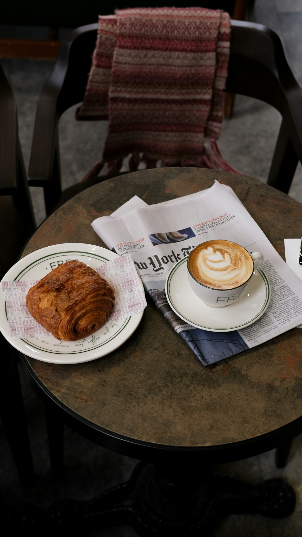 Mesa con una taza de café y un croissant