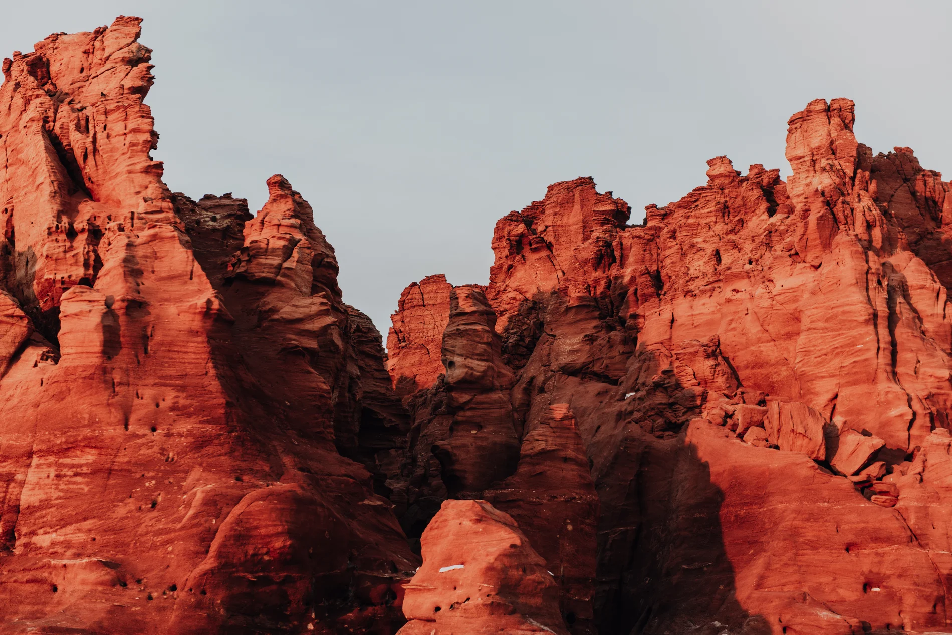 Weathered red sandstone pinnacles standing against a pale sky