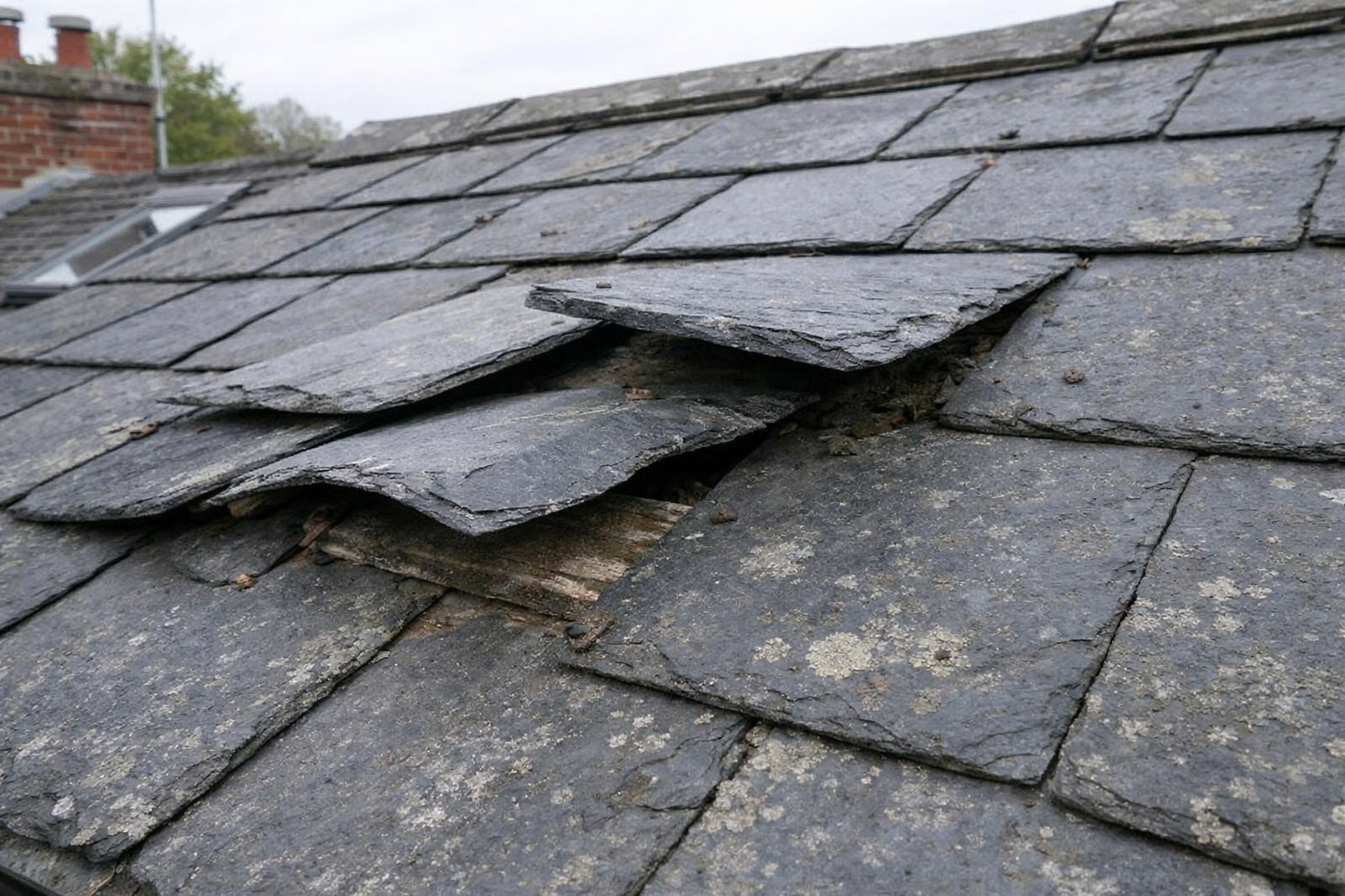 Ardoises de toiture qui se soulèvent sur un toit ancien après dégradation et soulèvement localisé