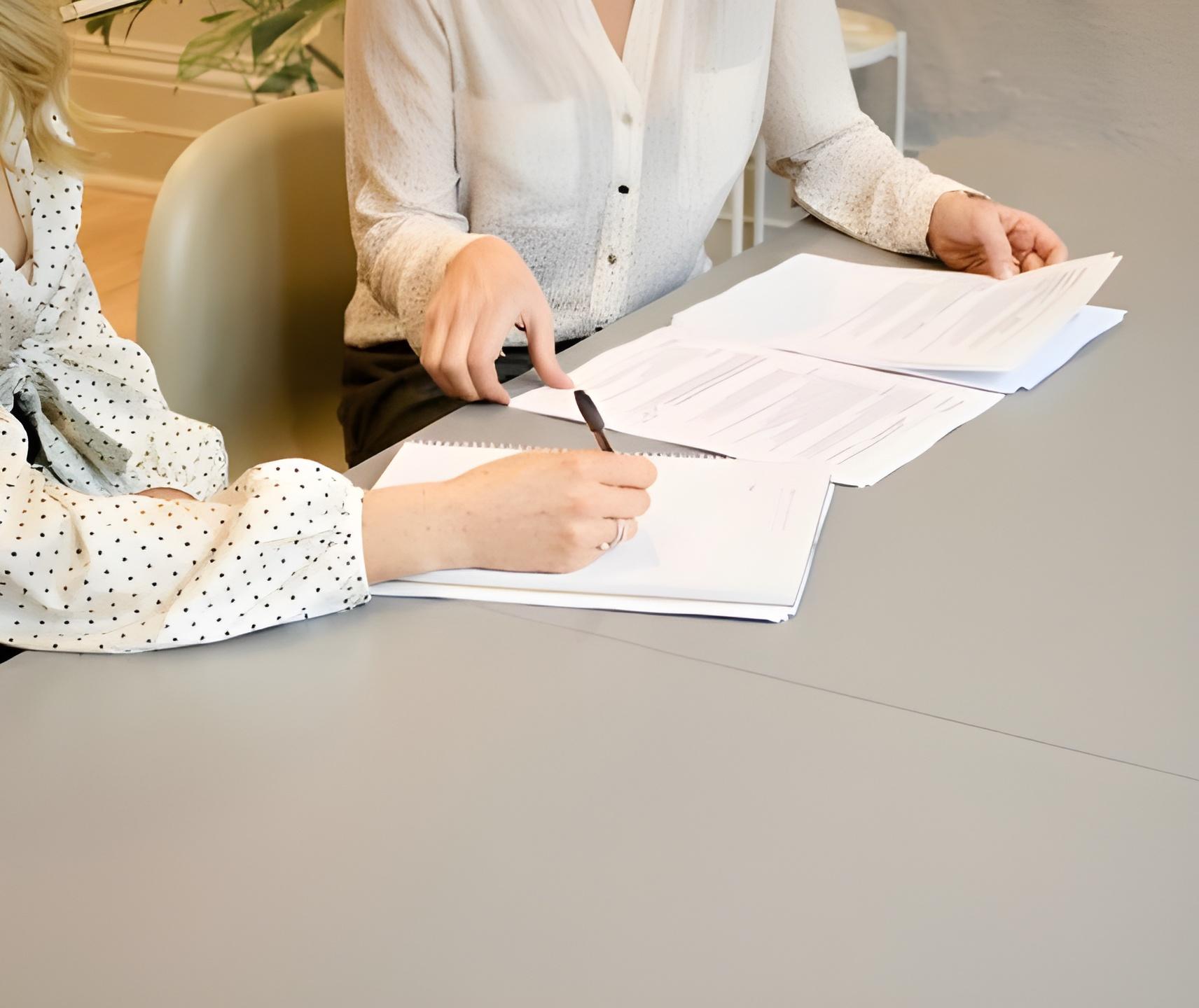 Two people reviewing documents at a desk — Empatia legal support for psychologists on labor rights, contract review, and employment conditions.