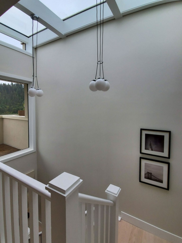 Image of KHD Homes interior design featuring a modern staircase with pendant lights and framed wall art.