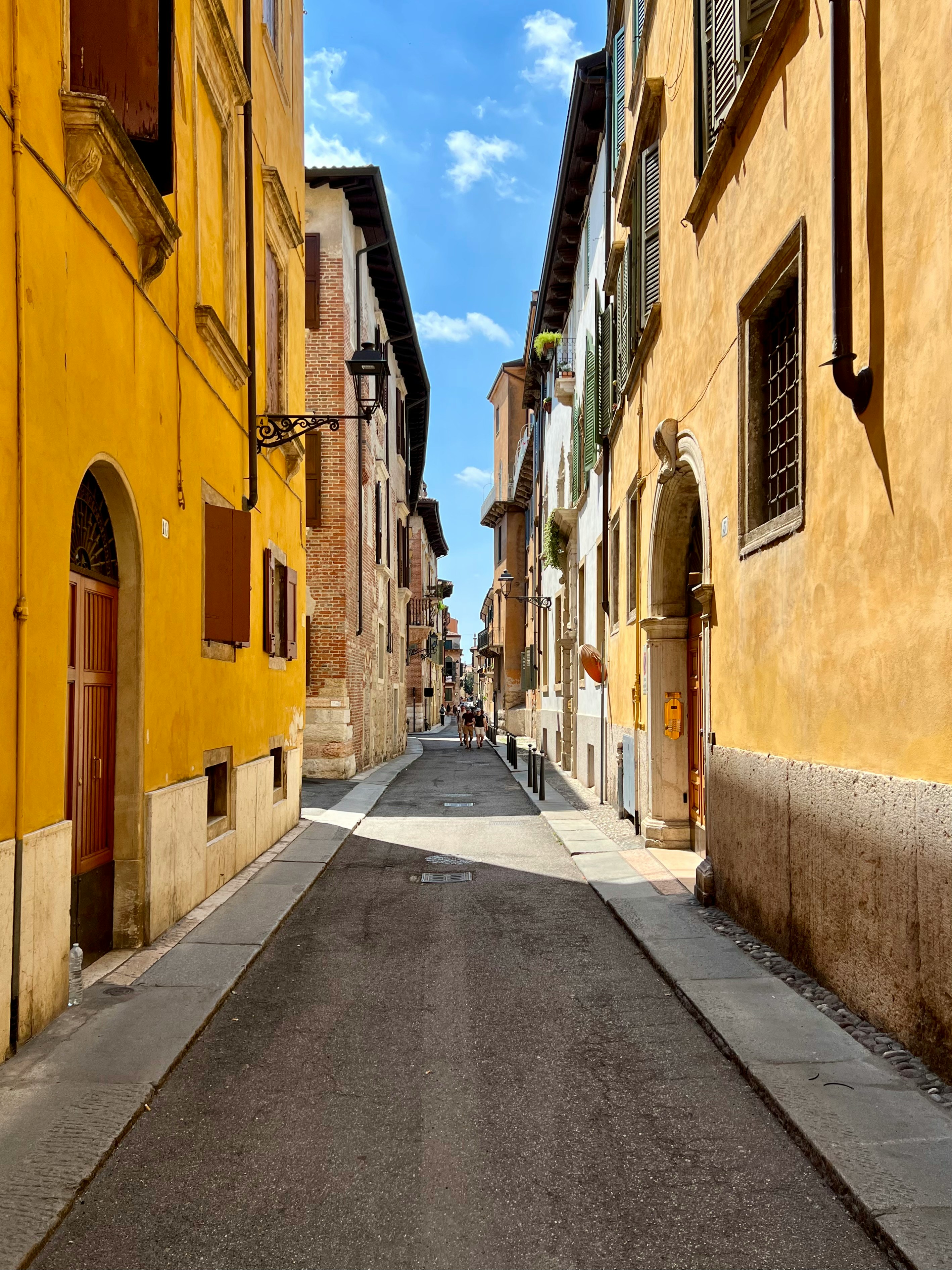 a narrow city street lined with yellow buildings