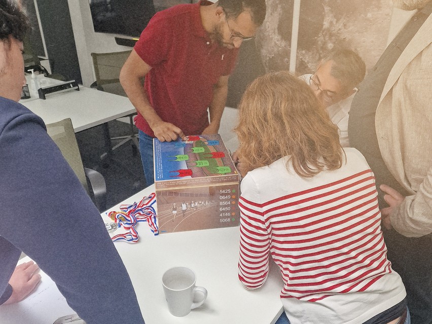 Des personnes en train de résoudre des énigmes en équipe, avec des médailles colorées sur la table.