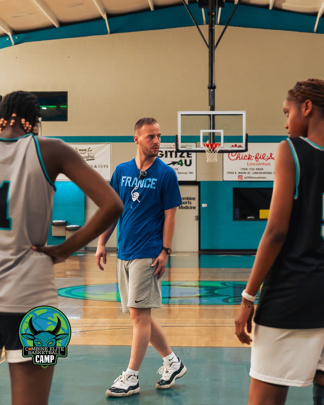 Entraîneur de basket discutant avec des joueurs pendant un camp d’entraînement.