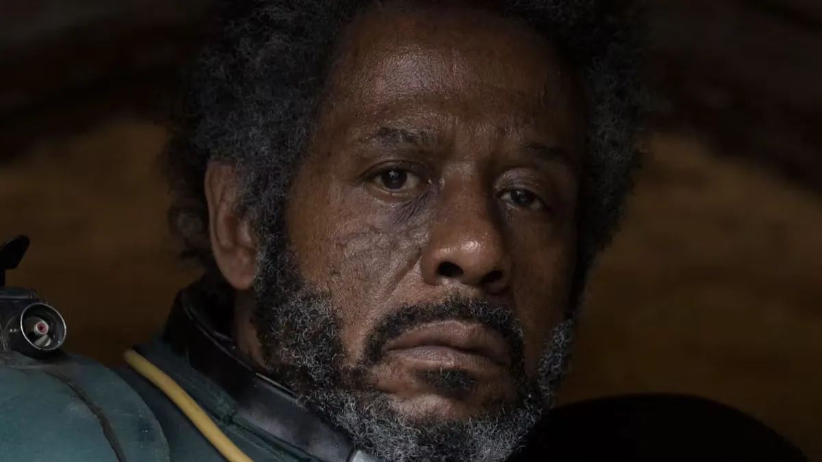 A close-up of Saw Gerrera, showing his weathered face, battle scars, and breathing apparatus as he plans his next move against the Empire