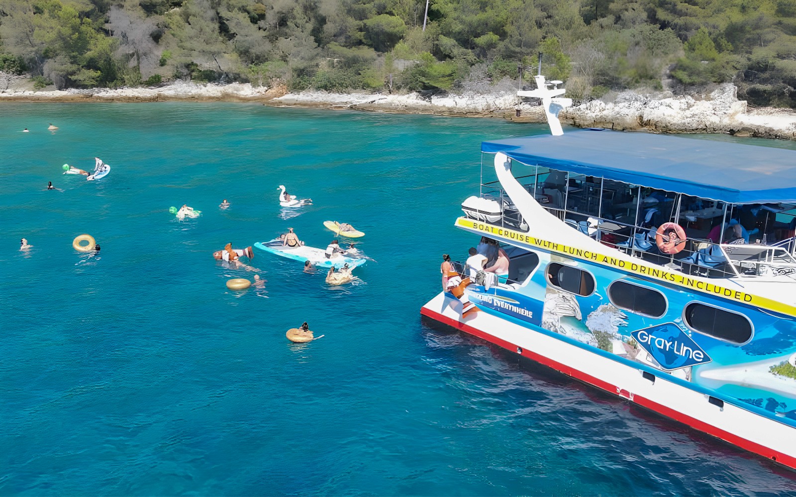 Tourists swimming near a cruise boat in Split, Croatia, with inflatable floats and nearby islands.
