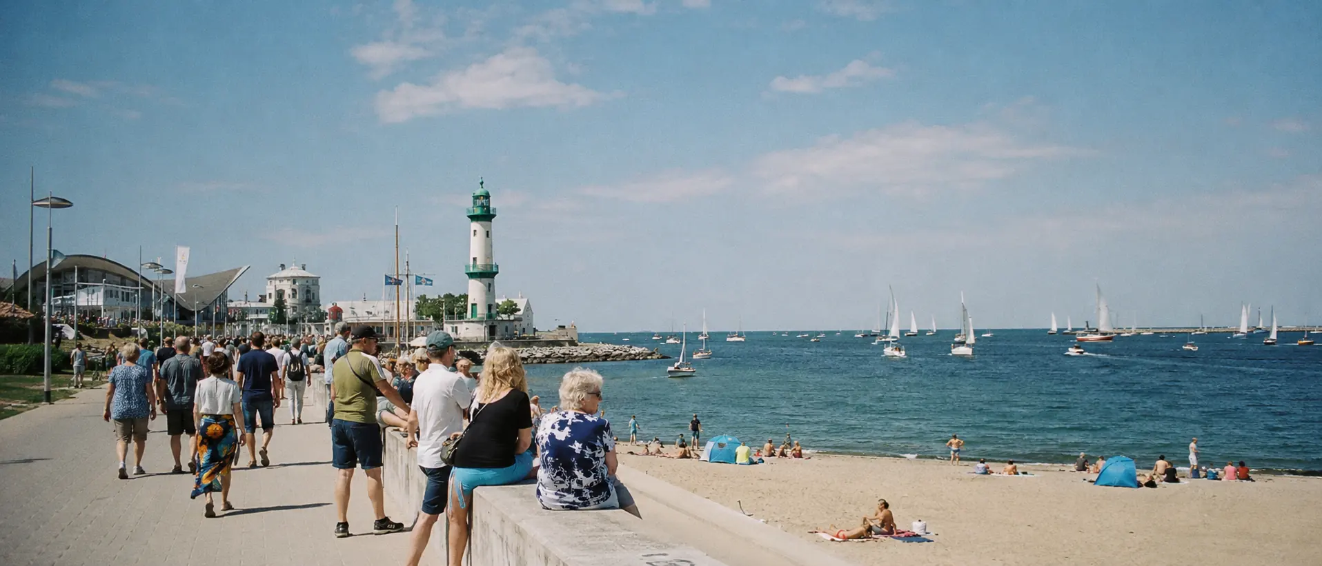 Warnemünde bei Rostock mit Leuchtturm, Segelbooten und Strandpromenade im Tageslicht