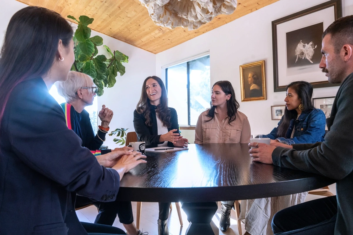 a group therapy session sitting around a table in a relaxed setting with diverse and modern art hanging on walls with plants in room representing group therapy for lgbtq support in a safe and inclusive environment