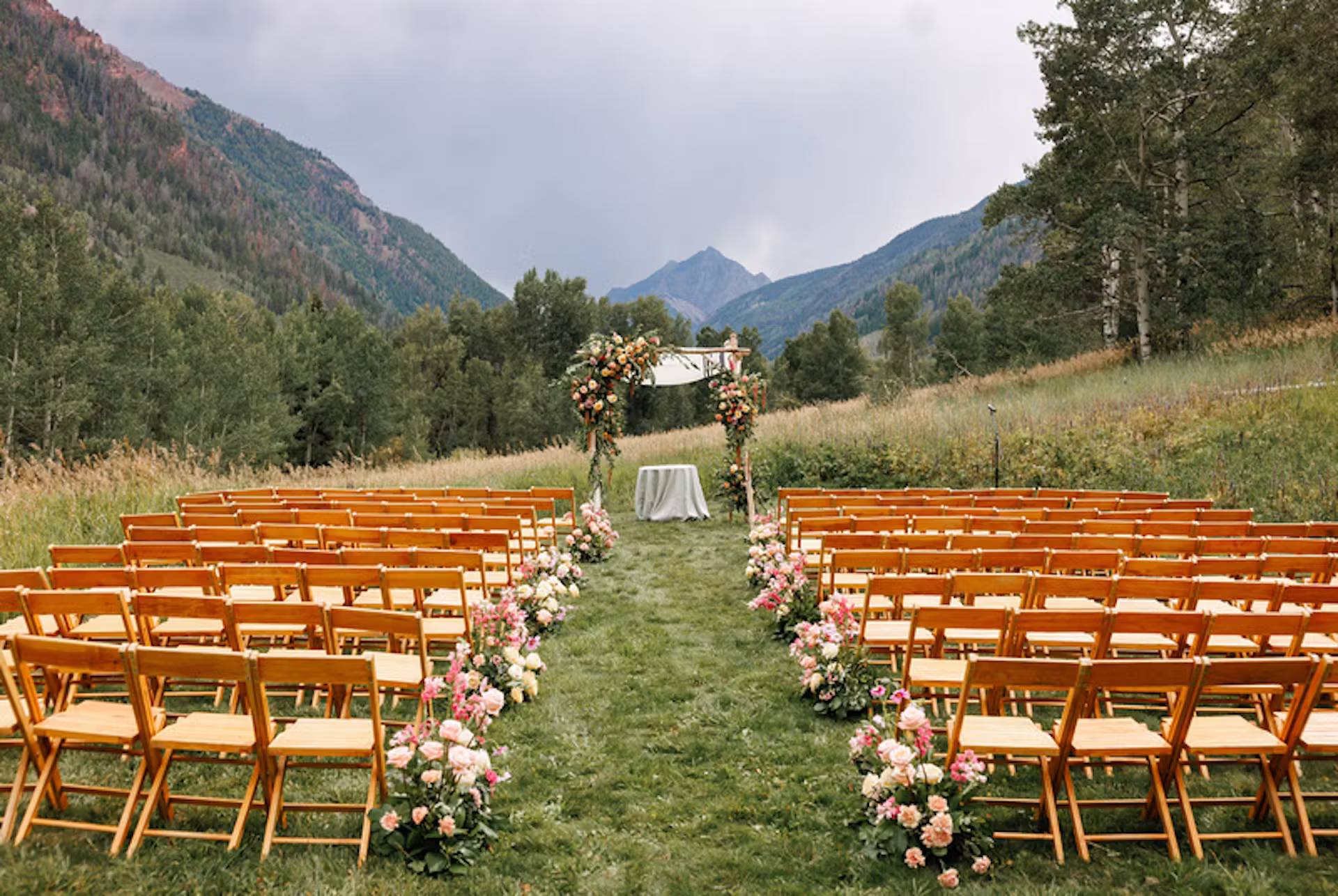 Outdoor mountain wedding ceremony at T Lazy 7 Ranch with a floral arch and alpine views