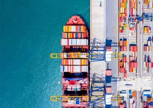 A full container ship docked in a port with many containers and ready to unload containers
