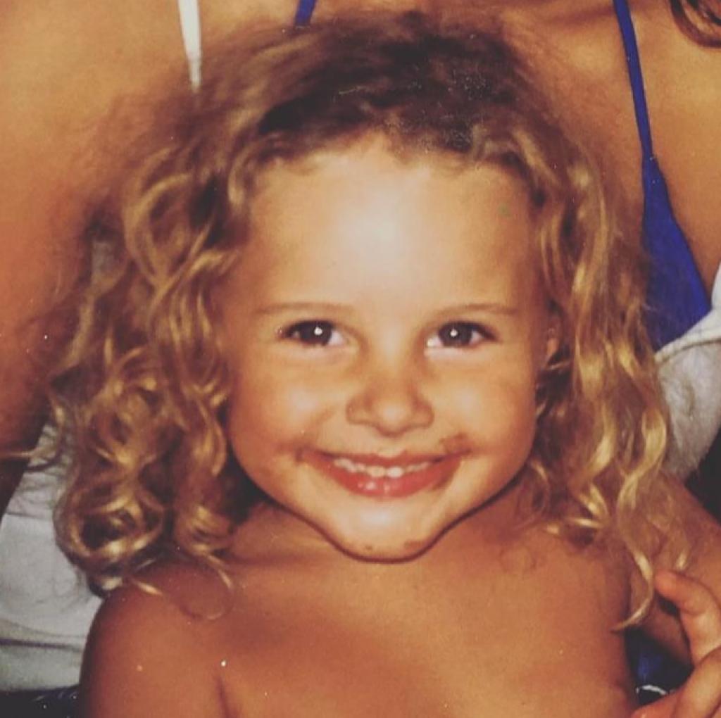 niña con pelo rubio rizado y sonriendo con la boca manchada de chocolate