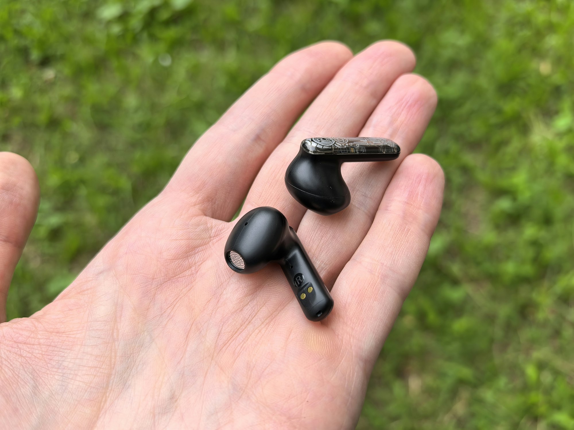 A hand holding a pair of black wireless earbuds in an open palm
