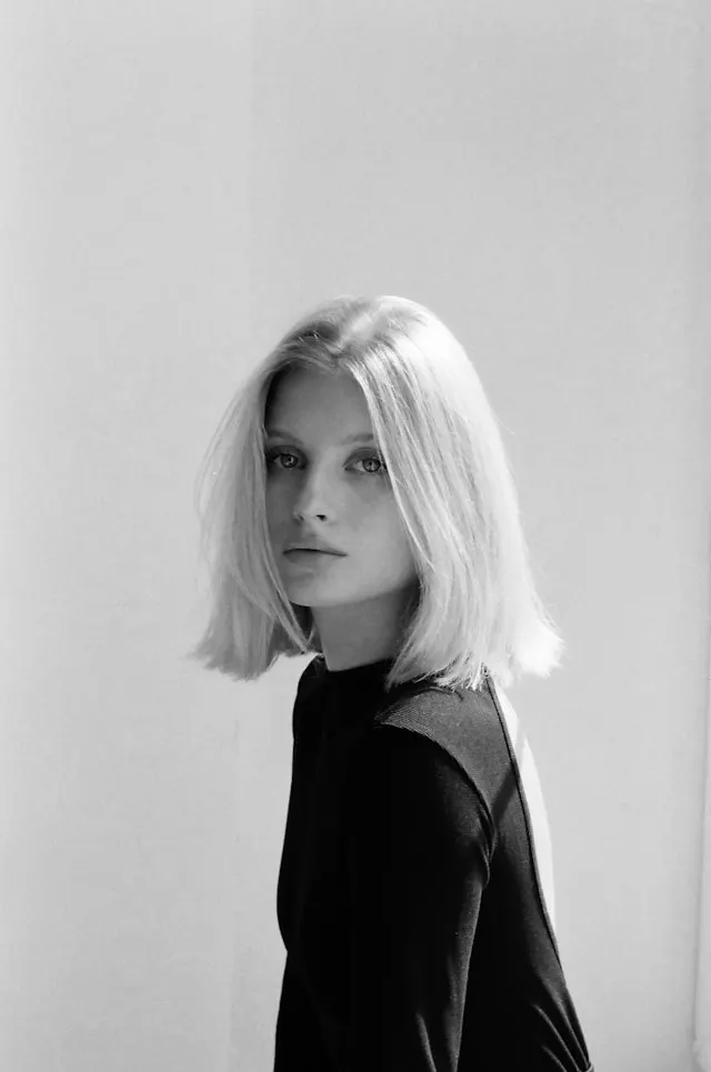 Blonde woman with bob haircut looking directly forward.