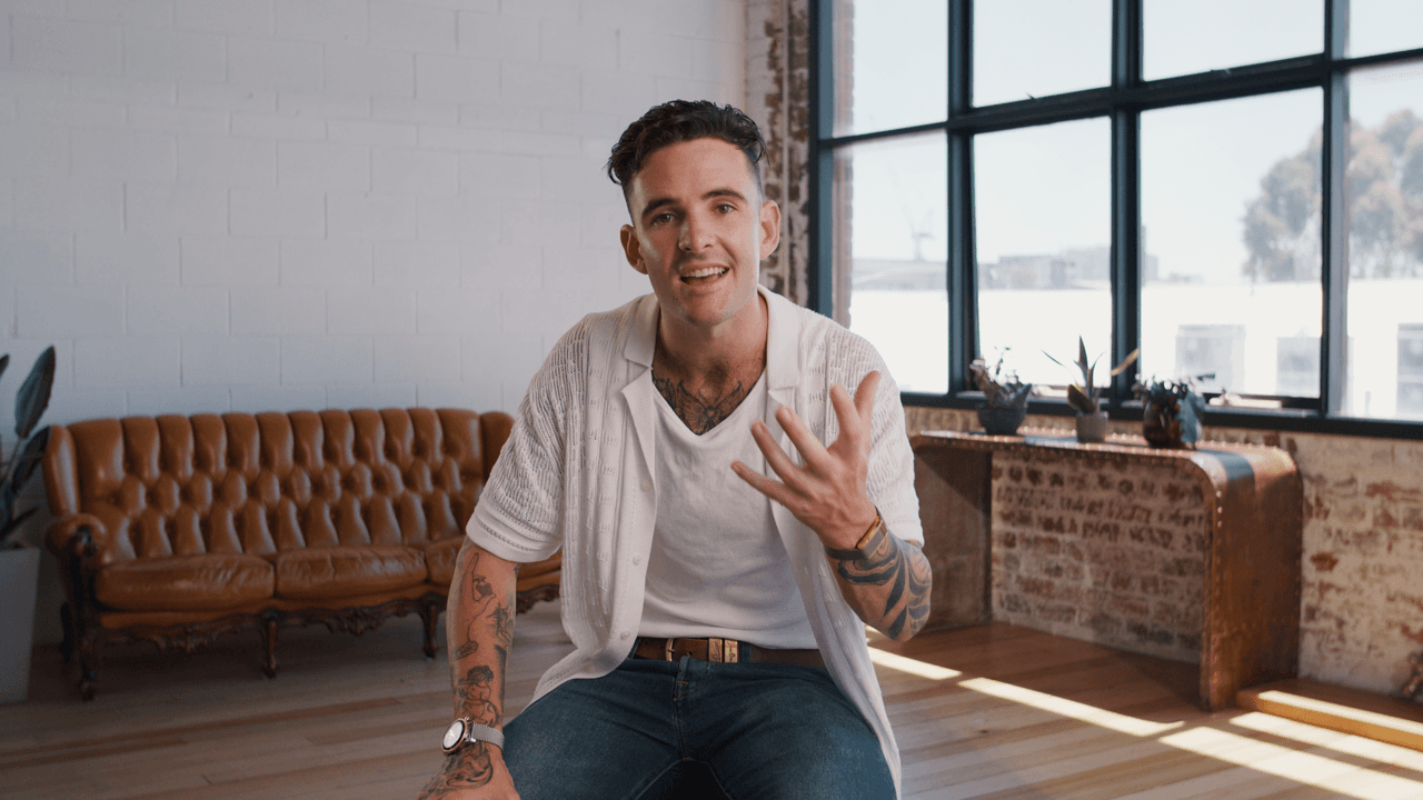 Tom Noske wearing a white shirt with a couch in the background