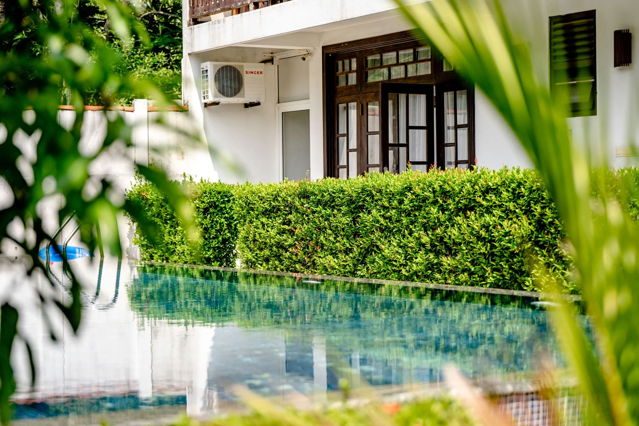 Exterior view of the garden triple room near the swimming pool and tropical greenery.