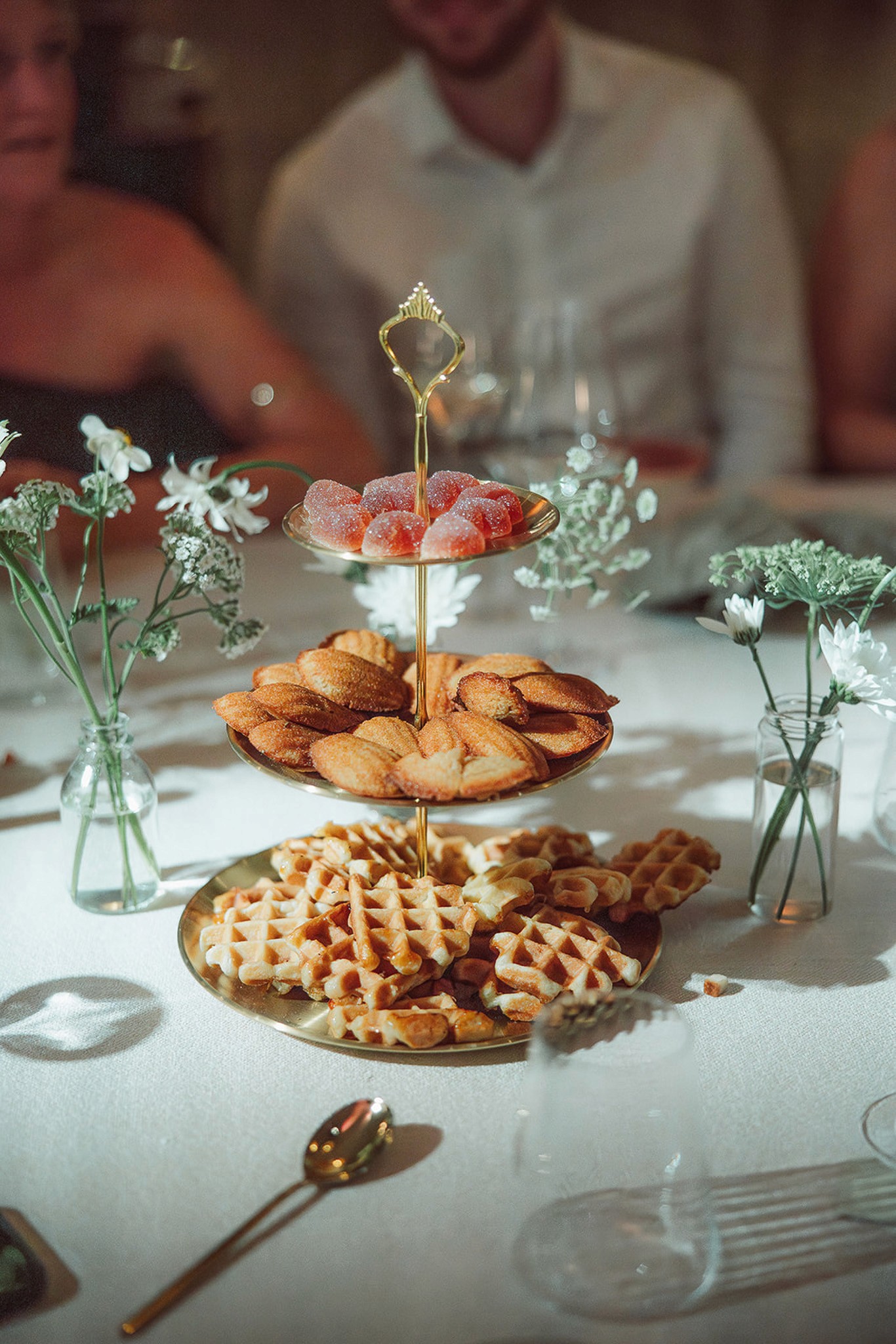 Restaurant interior with wooden tables and chairs lined against a textured wall, softly lit by round wall lamps.