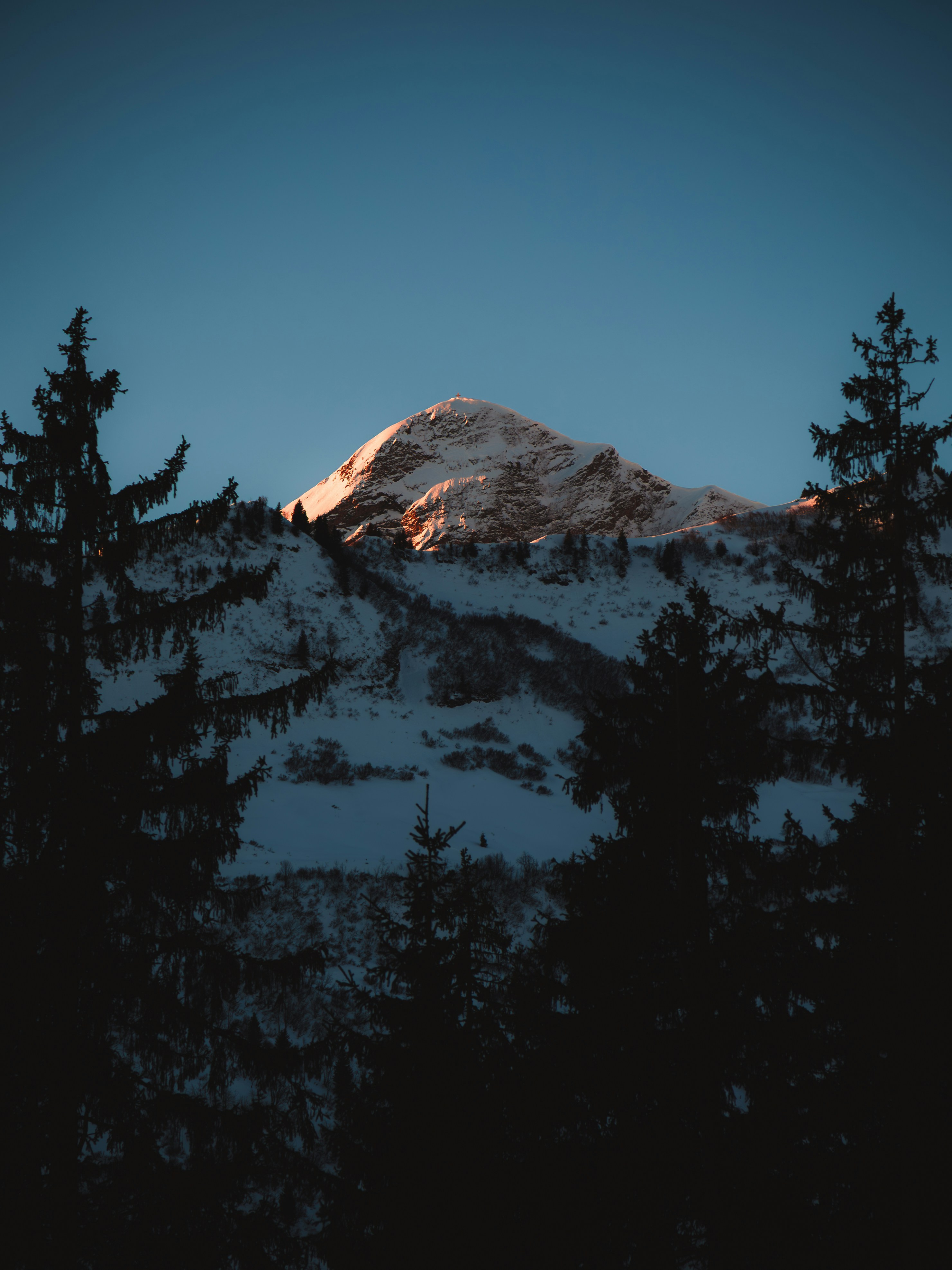 Snowy mountain peak illuminated by sunset light