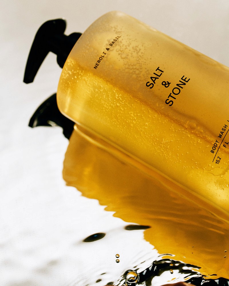 Yellow perfume bottle photographed with black liquid and graphic reflections