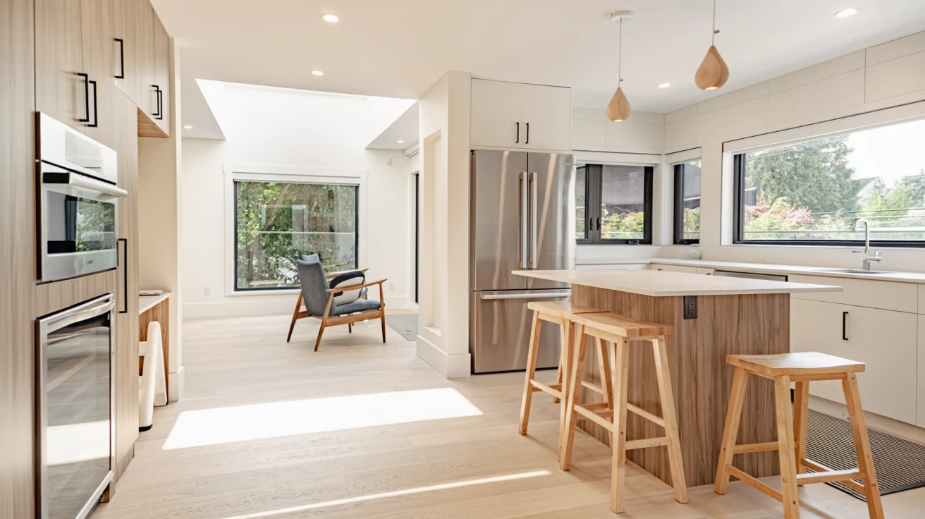 Open concept modern kitchen with island seating, built-in appliances, hardwood floors, and views throughout Metro Vancouver home