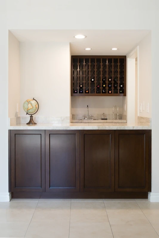 Elegant wine nook with dark cabinetry, stone backsplash, and vertical wine storage in Orange Interior Remodel.
