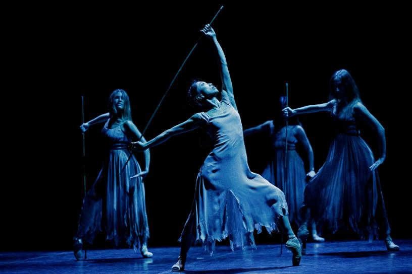 Dancer leading a powerful staff routine in a blue lit scene from Akram Khans Giselle.